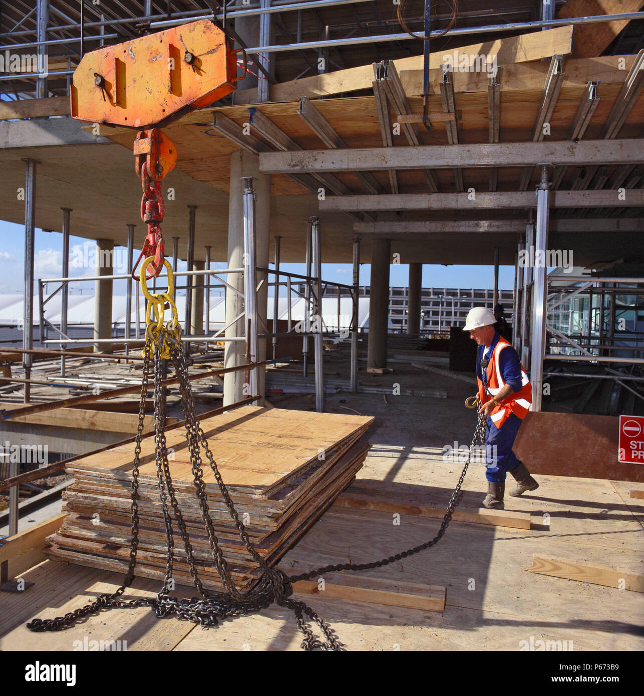 Banksman bereitet Last von Schnittholz Schalung für ifting auf der Baustelle von Beton - gerahmte Office Block Stockfoto