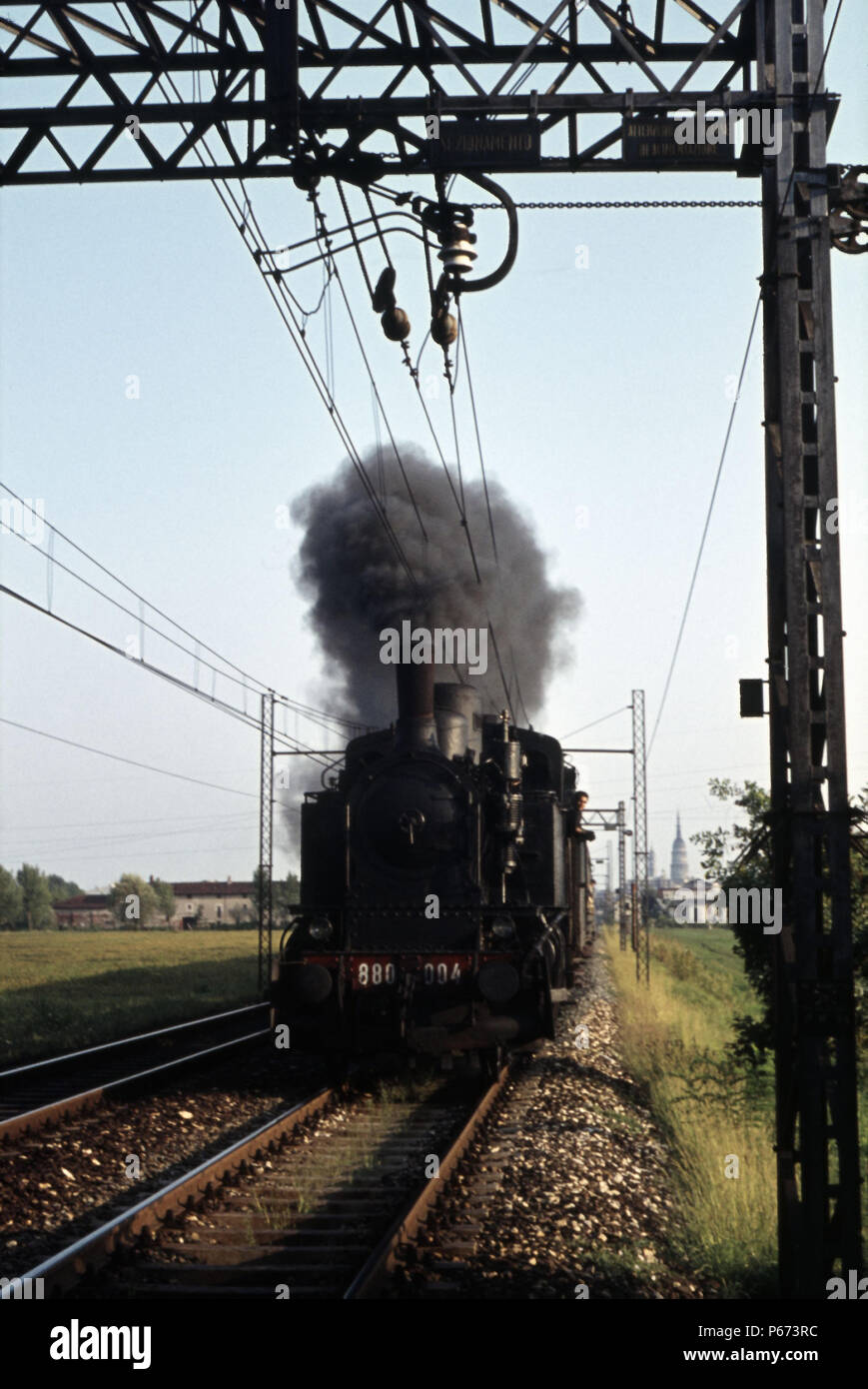 Eine Italienische Eisenbahn 880 Klasse 2-6-0 T leitet ein Personenzug mit Novara Stadt Dom im Hintergrund. Stockfoto