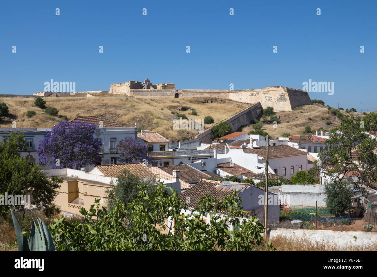 Häuser von Castro Marim und einem Ausblick auf die mittelalterliche casle auf dem Hügel mit dem gleichen Namen, durch die Schutzmauer umgeben. Strahlend blauen Himmel. Castro Marim, Stockfoto