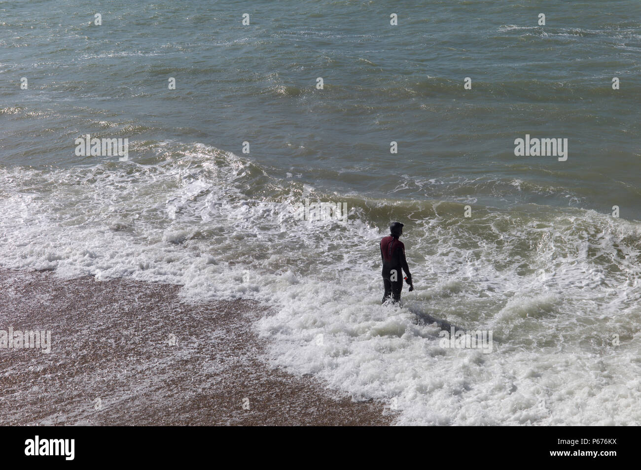 Mann in Anzug Vorbereitung im rauen Wasser zu schwimmen, Brighton, Großbritannien Stockfoto