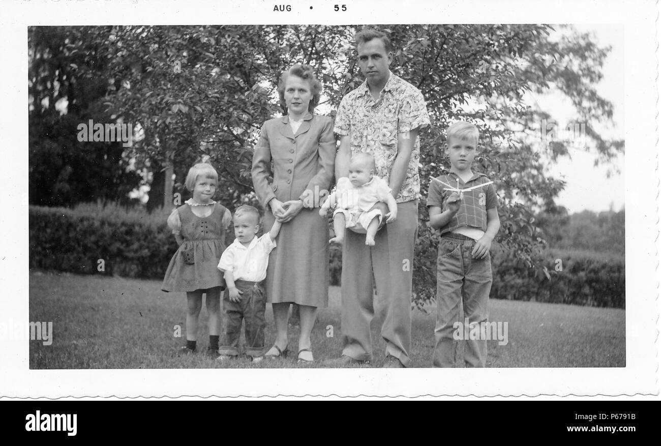 Schwarz-weiß Foto, außen mit einer großen Familie in einer grünen Umgebung, einschließlich ein Mann mit einem geblümten Hemd und Hose, und eine Frau mit kurzen Haaren, trug einen Rock, der von vier blonde Kinder umgeben, jeder trägt einen ernsten Ausdruck, wahrscheinlich in Ohio, August, 1955 fotografiert. () Stockfoto