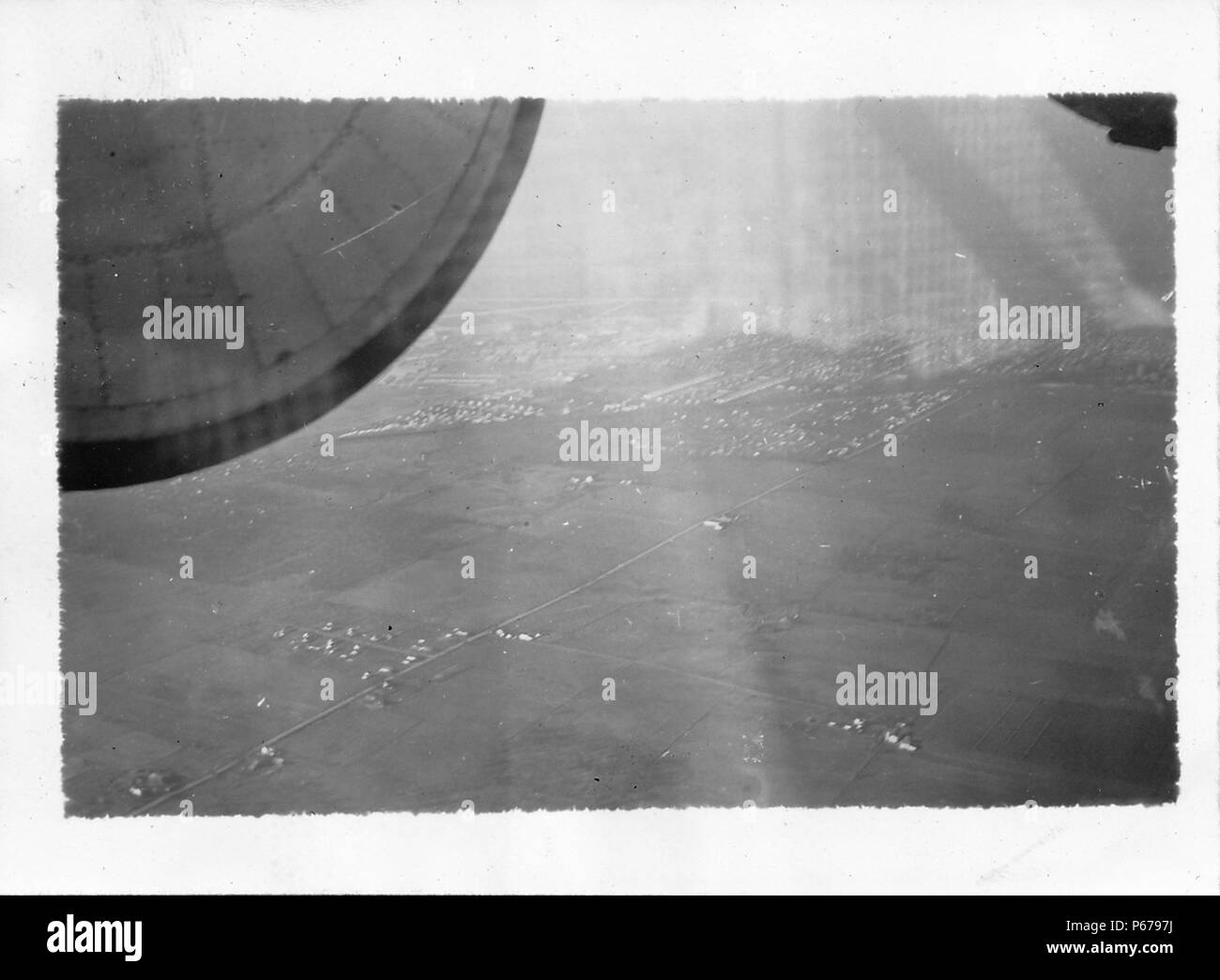 Schwarz-weiß Foto, geschossen vom Fahrzeuginnenraum aus einem Flugzeug im Flug, auf rechteckige Patches von flachen, teilweise kultiviert, teilweise besiedelten Landes, mit einem Teil des Motors in der oberen Vordergrund sichtbar, wahrscheinlich fotografierte während des Zweiten Weltkrieges, 1945. () Stockfoto