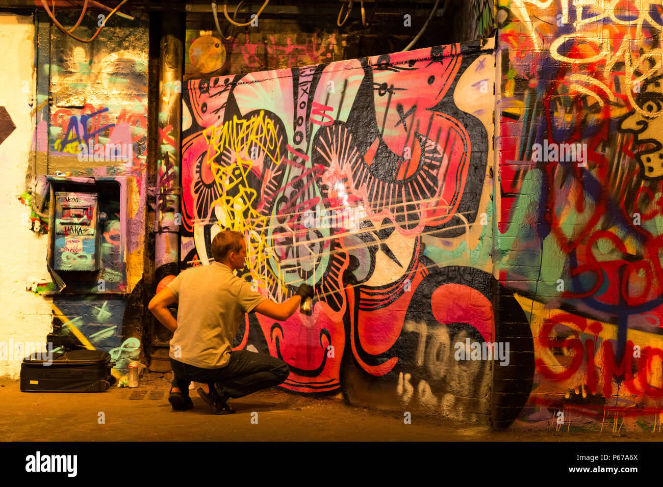 London Waterloo Leake Street Graffiti artist Sprühdose Maler Malerei grau grau silbernen Linien über alte Kunst in schwarz PVC-Handschuhe Stockfoto