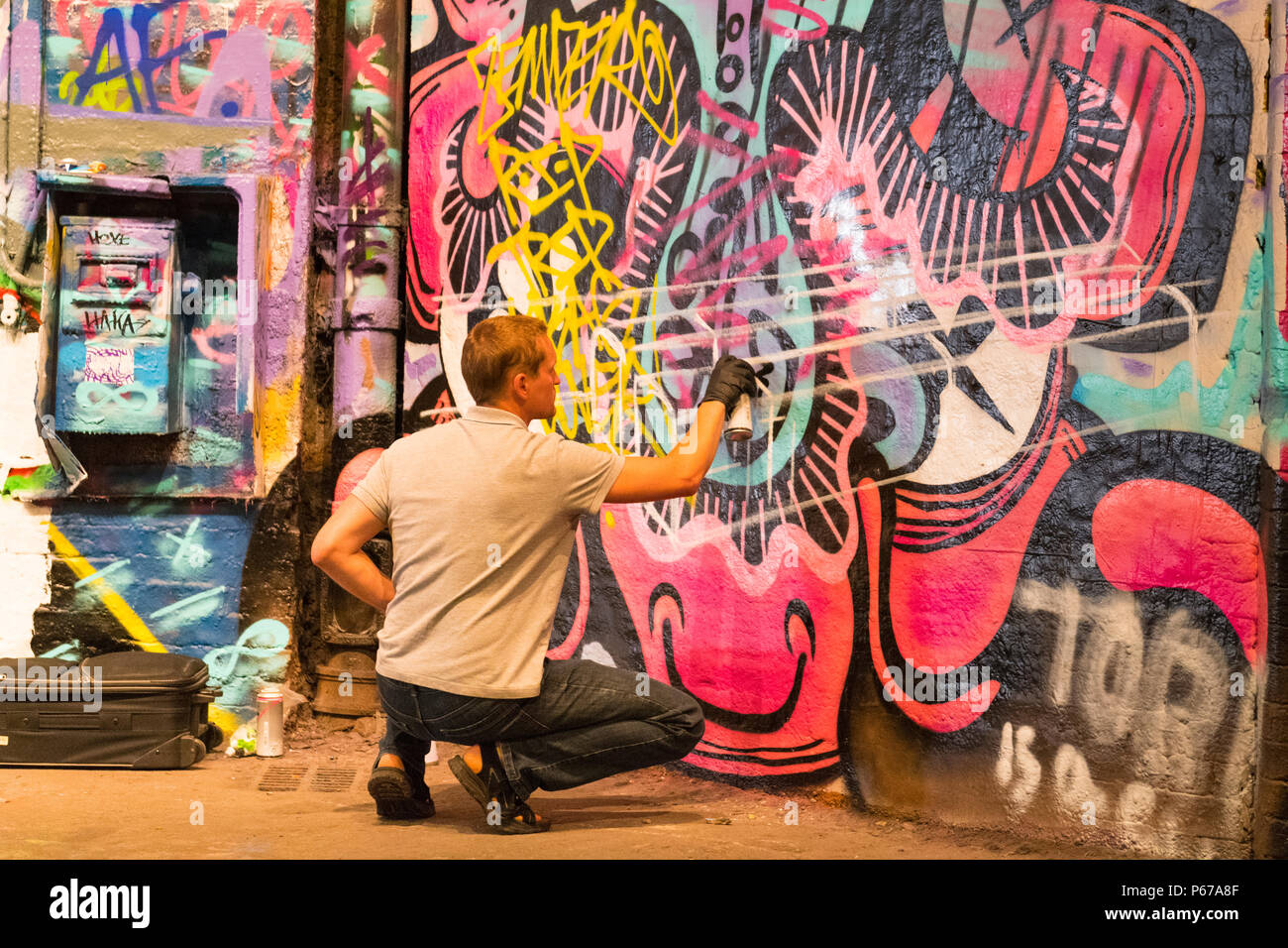 London Waterloo Leake Street Graffiti artist Sprühdose Maler Malerei grau grau silbernen Linien über alte Kunst in schwarz PVC-Handschuhe Stockfoto