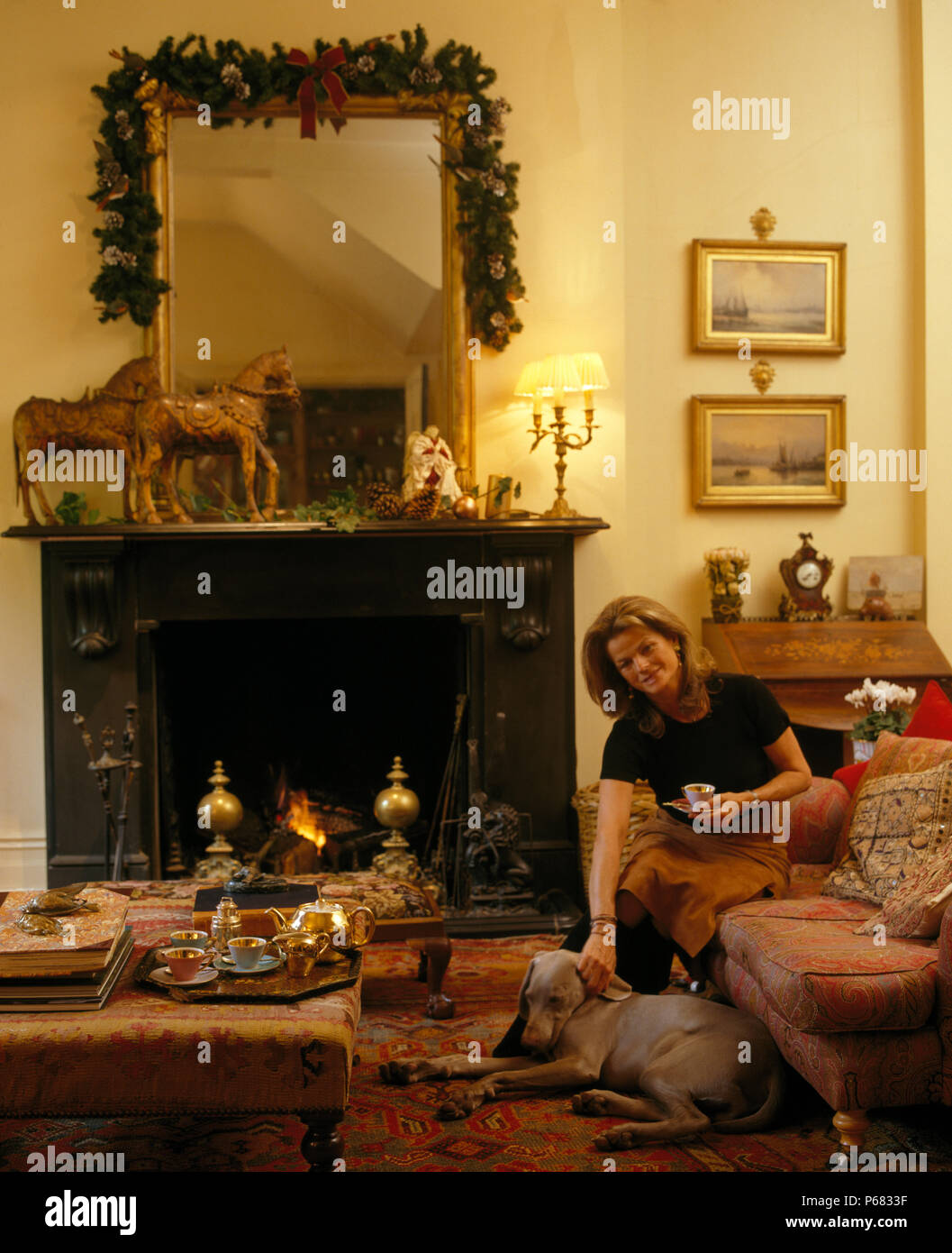 Frau sitzt mit weimaraner Hund im Wohnzimmer für Weihnachten für redaktionelle Verwendung eingerichtet Stockfoto