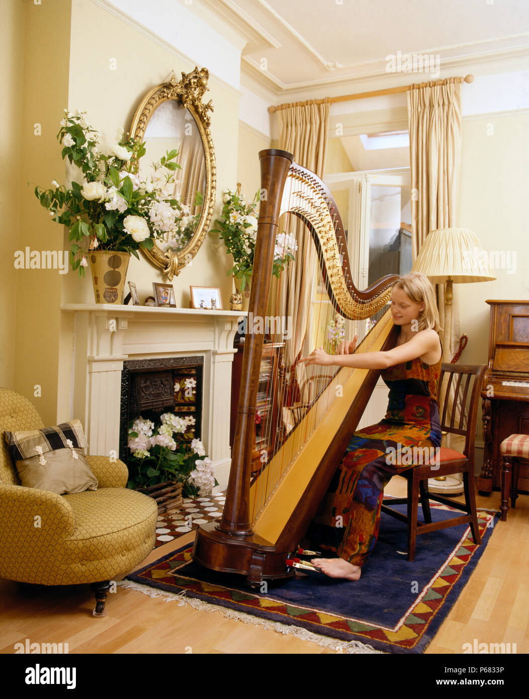 Junge Frau spielt die Harfe im Wohnzimmer für redaktionelle NUR VERWENDEN Stockfoto