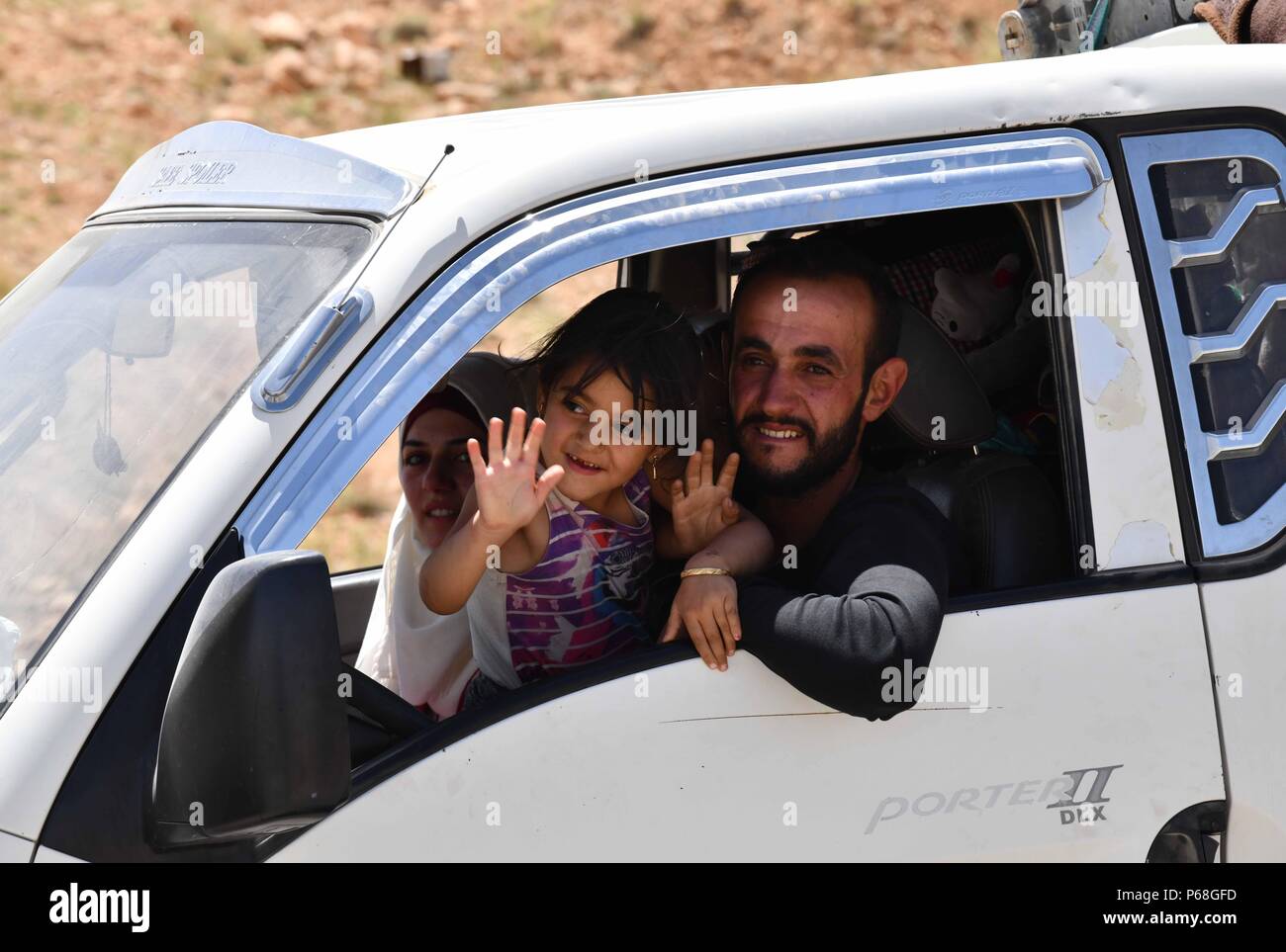 Damaskus, Syrien. 28 Juni, 2018. Eine syrische Mann und seine Tochter Welle ihre Hände, als sie zurück in Syrien durch die Zamrani Kreuzung zwischen der libanesischen Stadt Arsal und der syrischen Stadt Jarajir in der westlichen al-qalamoun Region, nördlich von Damaskus, der Hauptstadt von Syrien, am 28. Juni 2018. Rund 400 syrische Flüchtlinge in Libanon in ihre Heimat Donnerstag zurück von Arial auf Qalamoun über das Wadi Hmayed über private Busse, nach Elnashra, einem libanesischen Nachrichten Web site. Credit: Ammar Safarjalani/Xinhua/Alamy leben Nachrichten Stockfoto