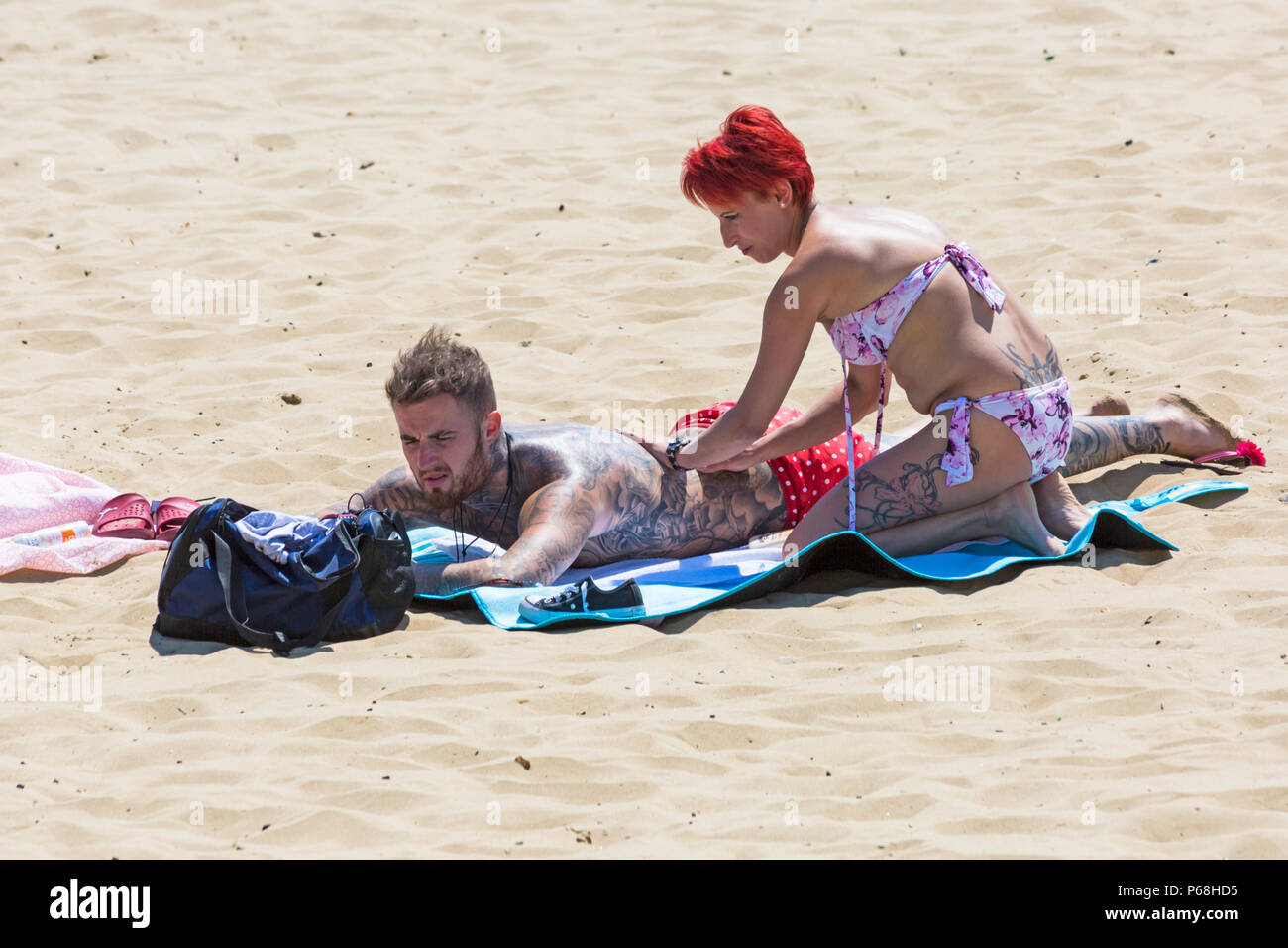 Bournemouth, Dorset, Großbritannien. 29. Juni 2018. UK Wetter: sunseekers Kopf bis zu den Stränden von Bournemouth auf einen weiteren sonnigen Tag mit Ungebrochenen blauer Himmel und Sonnenschein. Eine leichte Brise die Hitze erträglicher macht. Frau reiben Sonnencreme Creme auf Partner zurück. Credit: Carolyn Jenkins/Alamy leben Nachrichten Stockfoto