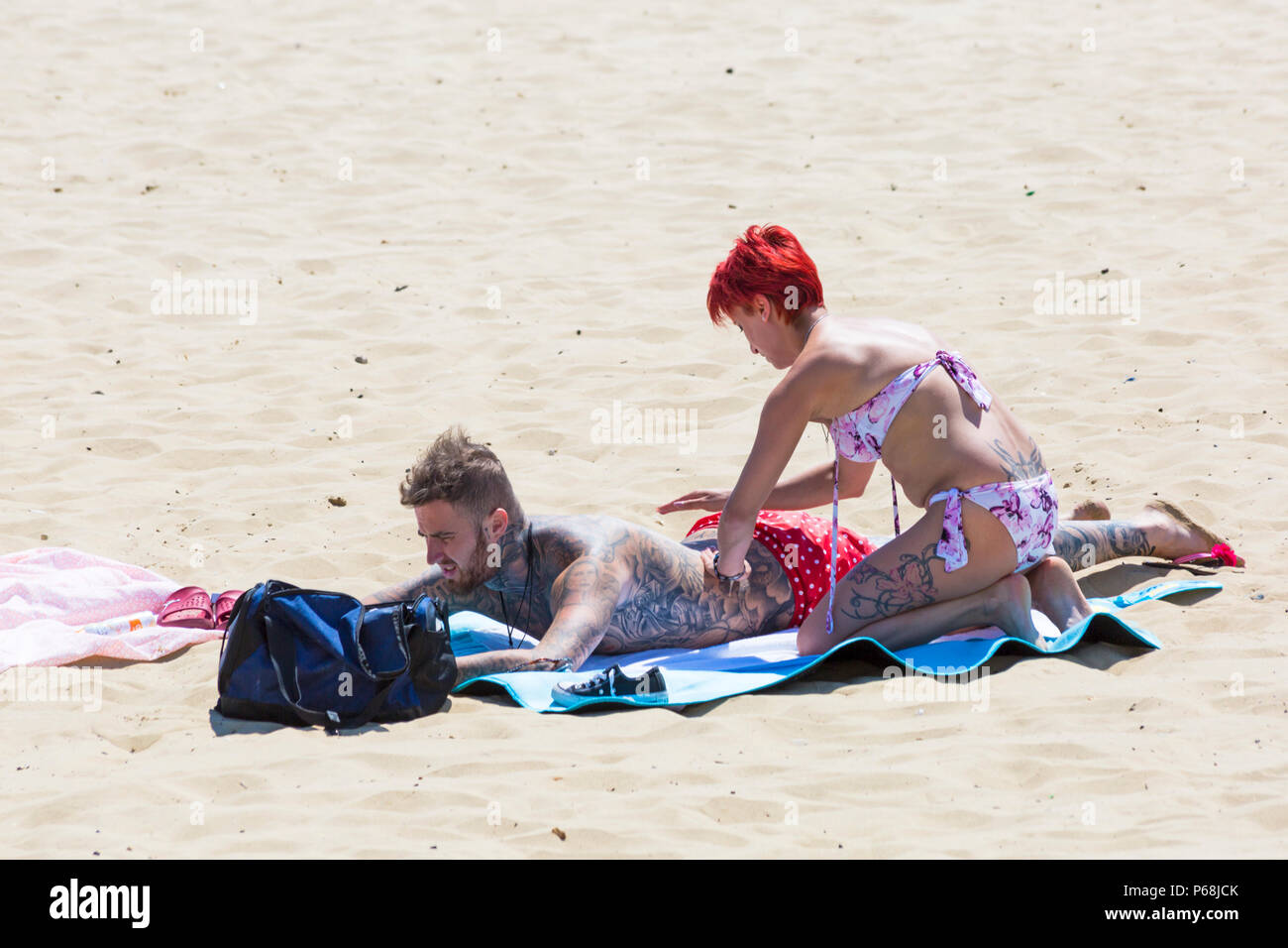 Bournemouth, Dorset, Großbritannien. 29 Juni, 2018. UK Wetter: sunseekers Kopf bis zu den Stränden von Bournemouth auf einen weiteren sonnigen Tag mit Ungebrochenen blauer Himmel und Sonnenschein. Eine leichte Brise die Hitze erträglicher macht. Frau reiben Sonnencreme Creme auf Partner zurück. Credit: Carolyn Jenkins/Alamy leben Nachrichten Stockfoto