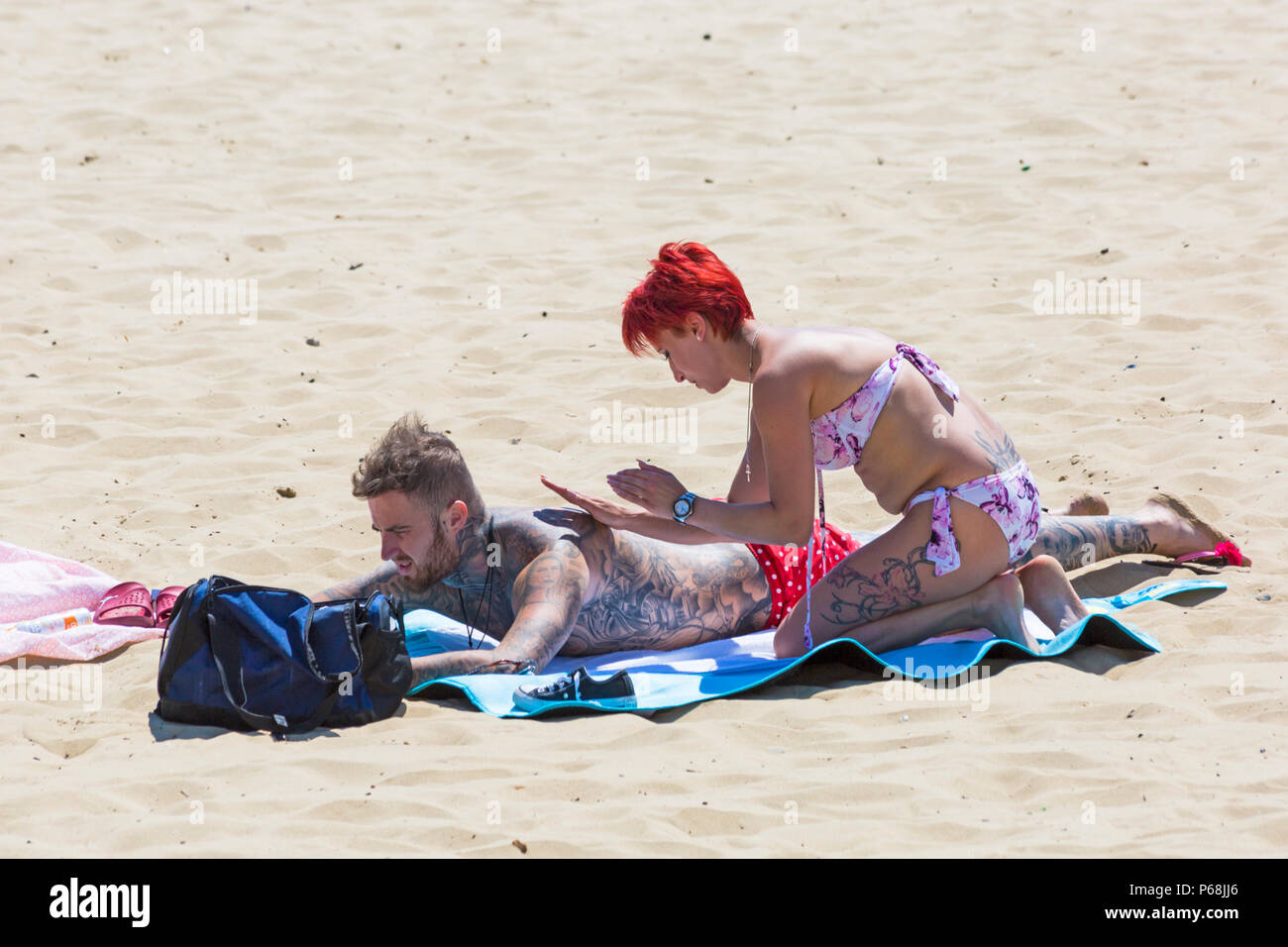Bournemouth, Dorset, Großbritannien. 29 Juni, 2018. UK Wetter: sunseekers Kopf bis zu den Stränden von Bournemouth auf einen weiteren sonnigen Tag mit Ungebrochenen blauer Himmel und Sonnenschein. Eine leichte Brise die Hitze erträglicher macht. Frau reiben Sonnencreme Creme auf Partner zurück. Credit: Carolyn Jenkins/Alamy leben Nachrichten Stockfoto