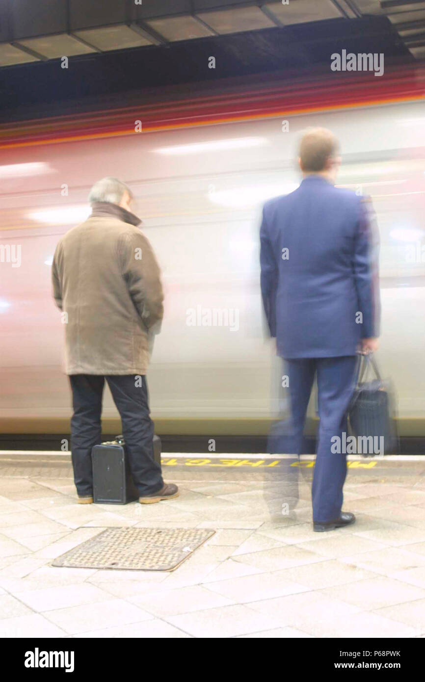 Zwei Pendler warten als Virgin Trains Voyager Service in Birmingham neue Straßen Plattform 9 ankommt. 2004. Stockfoto