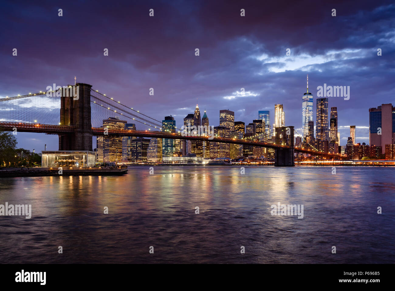 Brooklyn Bridge und Lower Manhattan beleuchtete Wolkenkratzer in der Dämmerung mit dem East River. Manhattan, New York City, USA Stockfoto