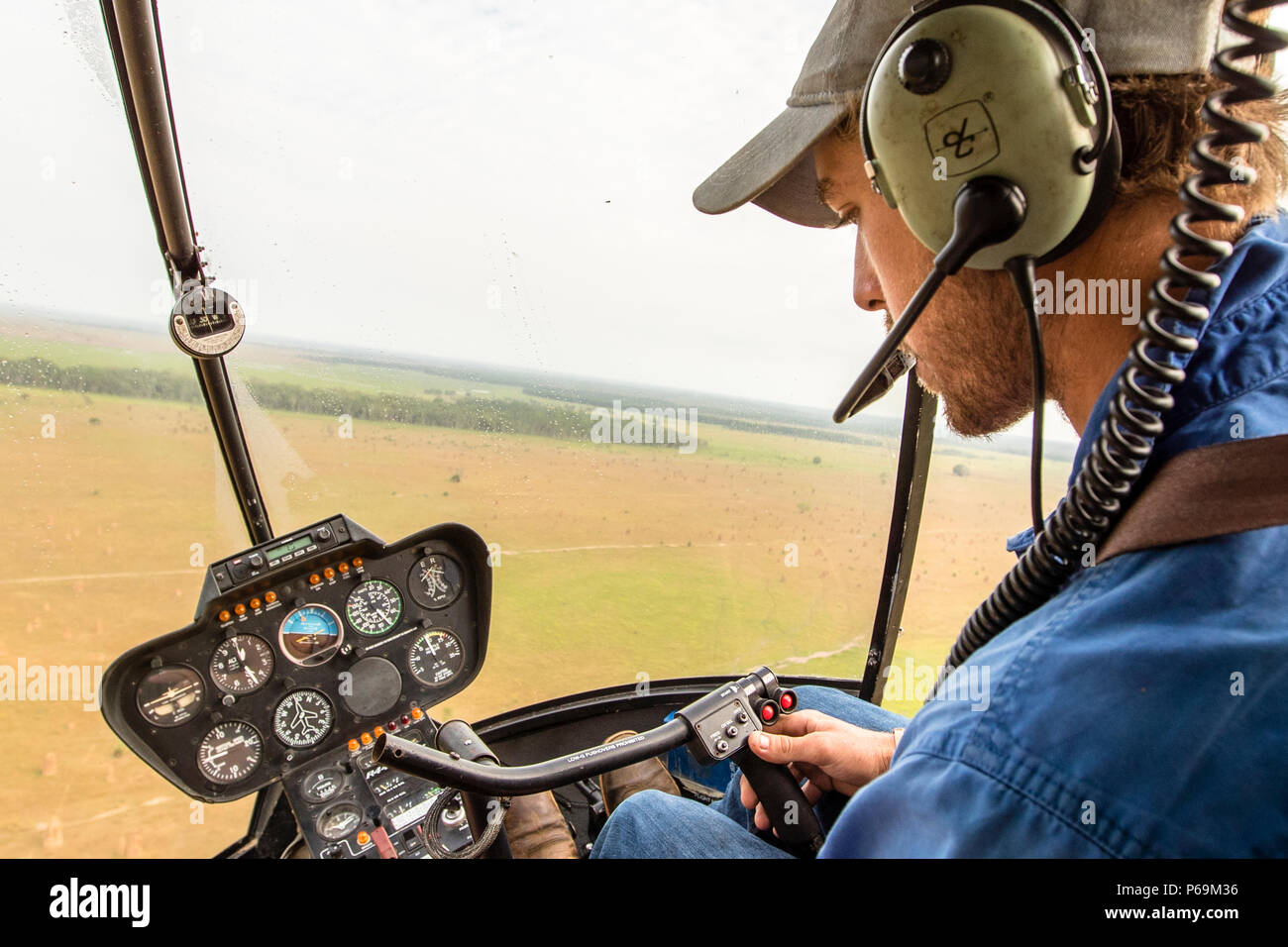 Jock am Steuerstick seines Robinson R44 Raven Hubschraubers im Northern Territory, Australien Stockfoto