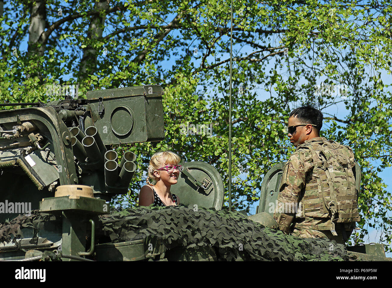 Eine lettische Mädchen sitzt in einem Stryker Armored Fighting Fahrzeug mit einem Soldaten zu F Troop, 2 Staffel, 2 Cavalry Regiment zugeordnet nach einer Demonstration für die Lettische militärische Familien während der Lettischen Bataillon Jahrestag, 28. Mai an Adazi Militärbasis, Lettland. Soldaten nahmen an der Demonstration neben lettischen Amtskollegen, während in der Region Unterstützung Betrieb Atlantic lösen, eine multinationale Demonstration der anhaltenden US-Engagement für die kollektive Sicherheit der North Atlantic Treaty Organisation (US-Verbündeten. Armee Foto von Sgt. Paige Behringer, 10 Drücken Sie lagern Hauptsitz Stockfoto