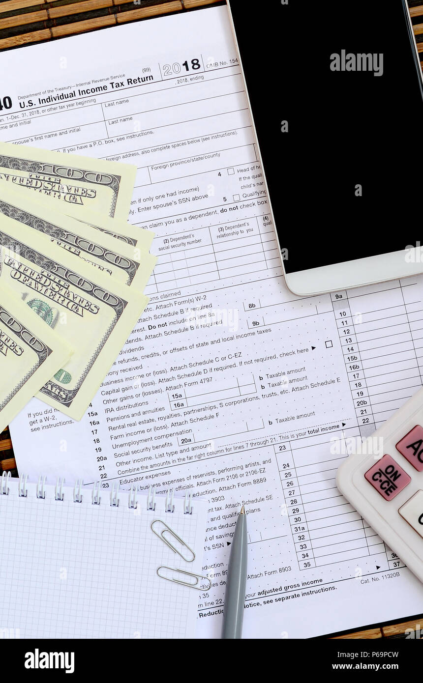 Zusammensetzung der Elemente liegen auf dem 1040 Steuerformular. Dollarscheine, Kugelschreiber, Taschenrechner, Smartphone, Büroklammer und Notepad. Die Zeit, die Steuern zu bezahlen. Stockfoto