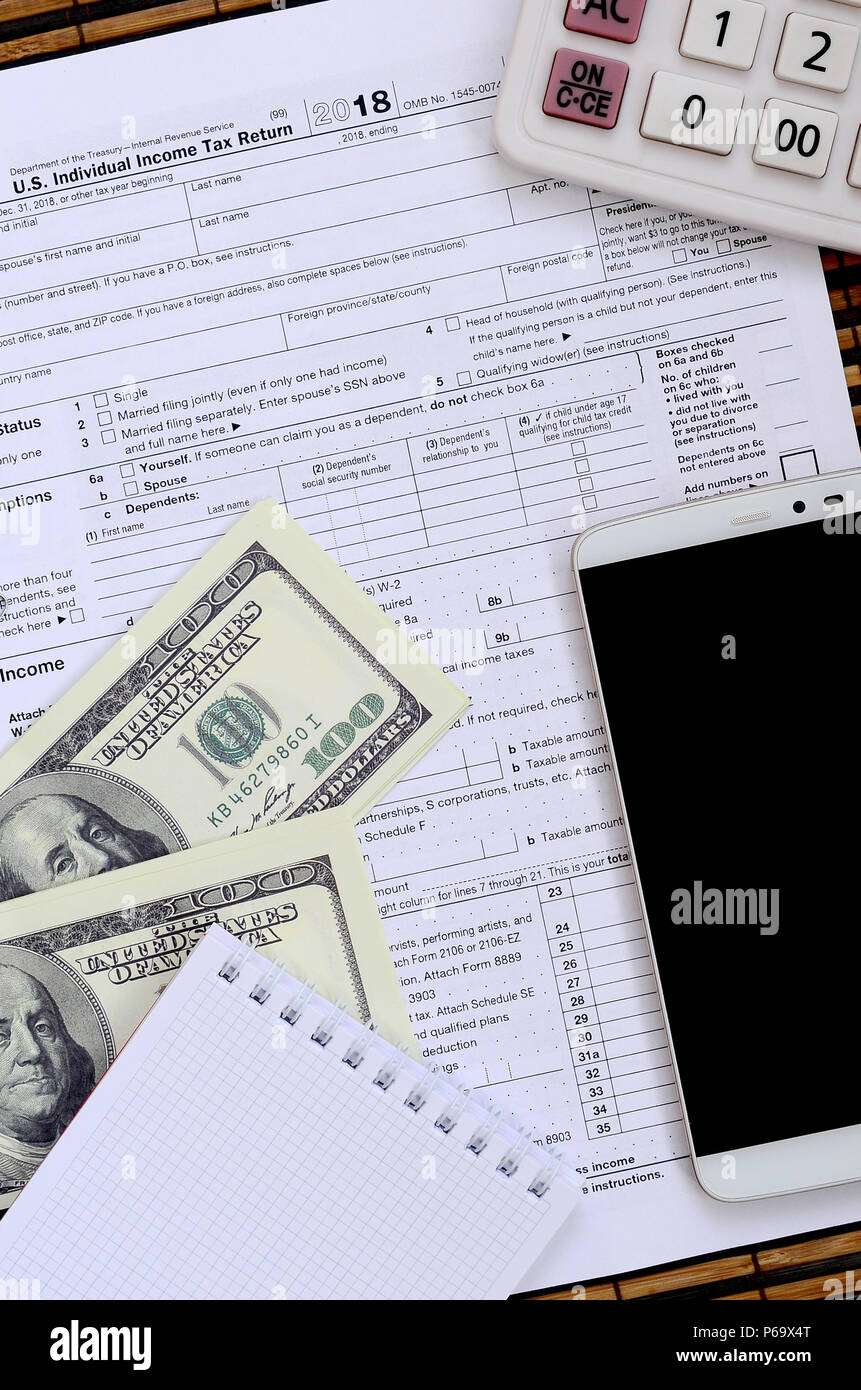 Zusammensetzung der Elemente liegen auf dem 1040 Steuerformular. Dollarscheine, Rechner, Smartphone, Büroklammer und Notepad. Die Zeit, die Steuern zu bezahlen. Stockfoto