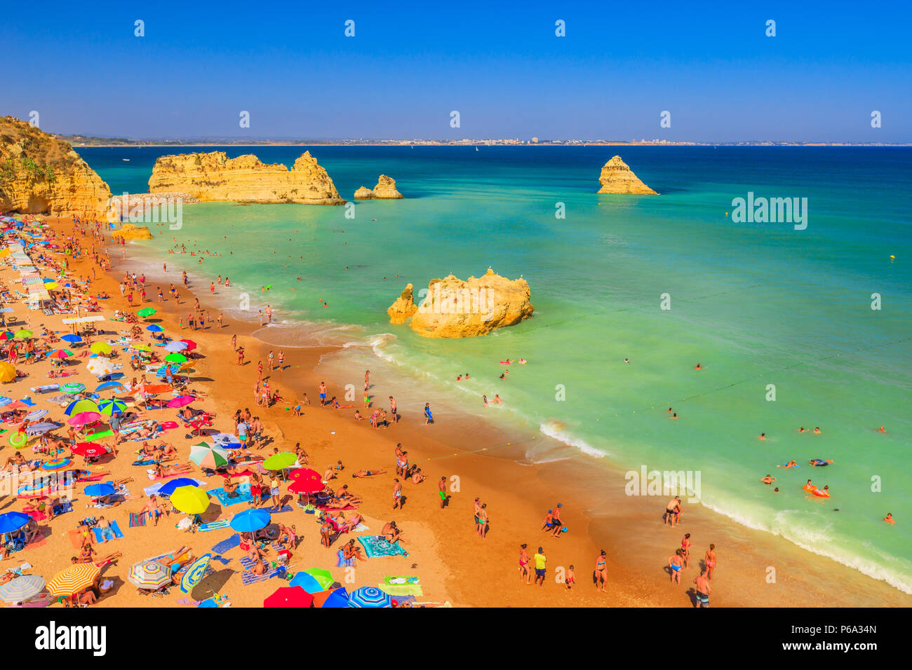 Lagos, Portugal - 21 August 2017: viele Menschen Sonnenbaden und genießen unter bunten Sonnenschirmen auf der beliebten Praia Dona Ana. Sommer Urlaub in der Algarve, Portugal. Stockfoto