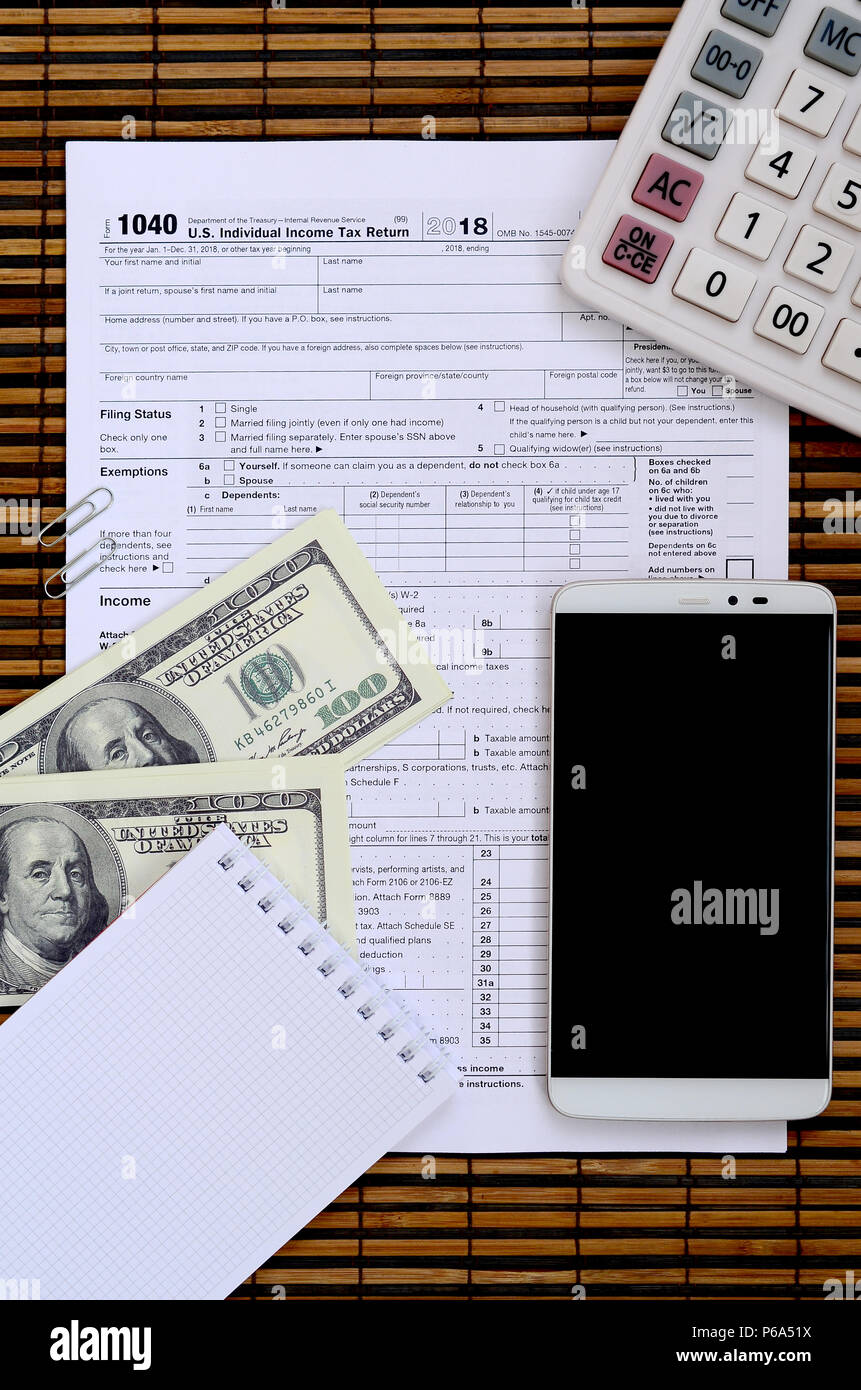 Zusammensetzung der Elemente liegen auf dem 1040 Steuerformular. Dollarscheine, Rechner, Smartphone, Büroklammer und Notepad. Die Zeit, die Steuern zu bezahlen. Stockfoto