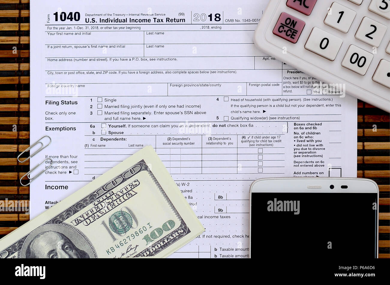 Zusammensetzung der Elemente liegen auf dem 1040 Steuerformular. Dollarscheine, Rechner, Smartphone, Büroklammer und Notepad. Die Zeit, die Steuern zu bezahlen. Stockfoto