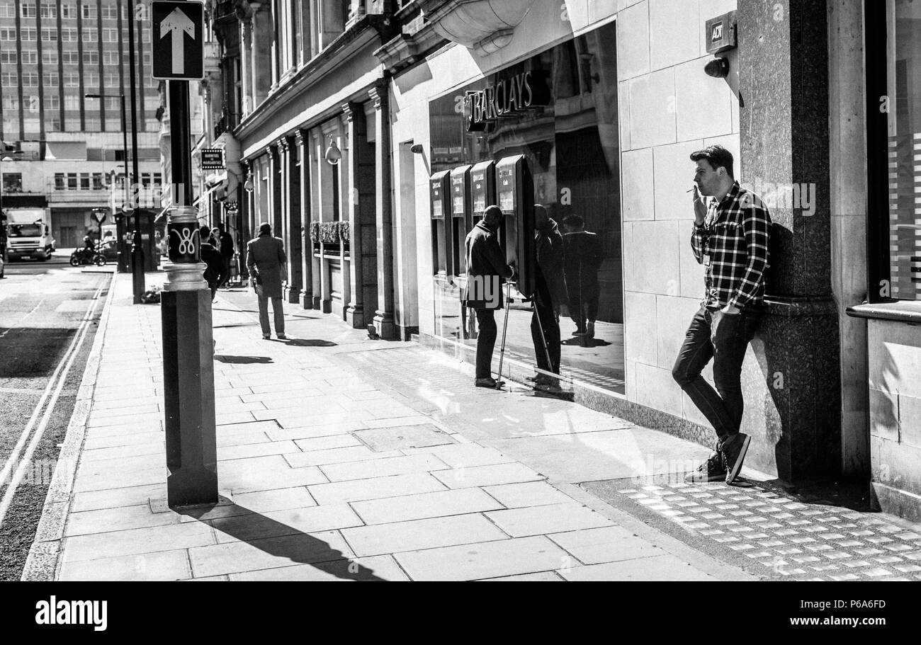 Ein Mann stand gegen eine Wand und eine Zigarettenpause, London, England, UK. Stockfoto