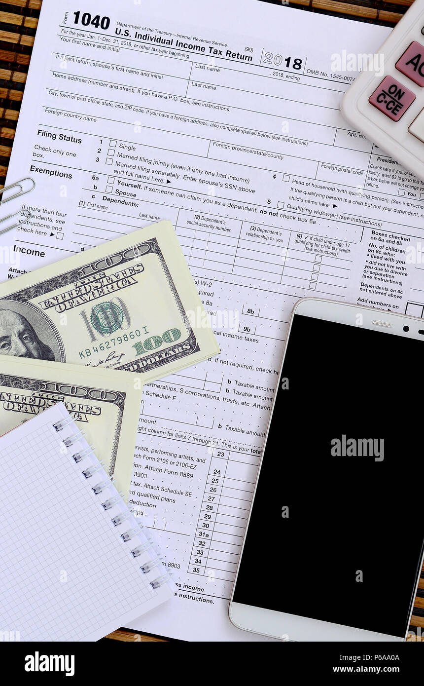 Zusammensetzung der Elemente liegen auf dem 1040 Steuerformular. Dollarscheine, Rechner, Smartphone, Büroklammer und Notepad. Die Zeit, die Steuern zu bezahlen. Stockfoto