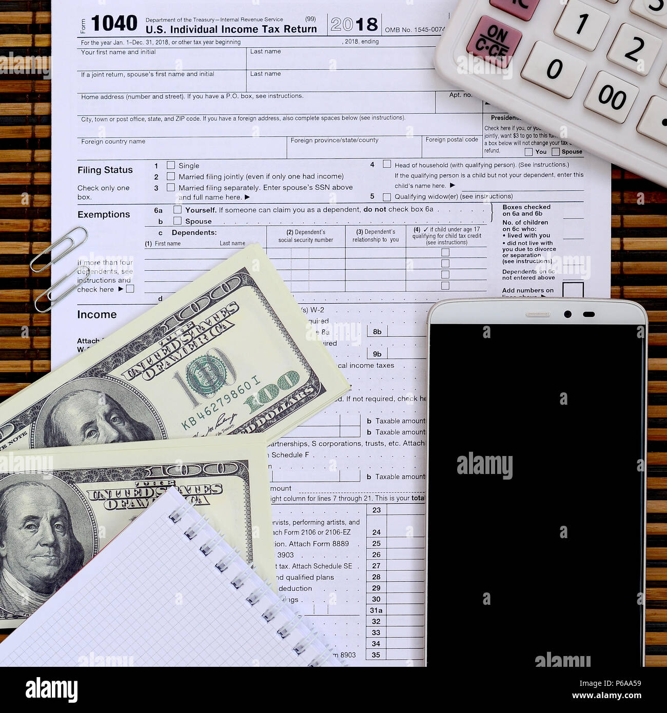 Zusammensetzung der Elemente liegen auf dem 1040 Steuerformular. Dollarscheine, Rechner, Smartphone, Büroklammer und Notepad. Die Zeit, die Steuern zu bezahlen. Stockfoto