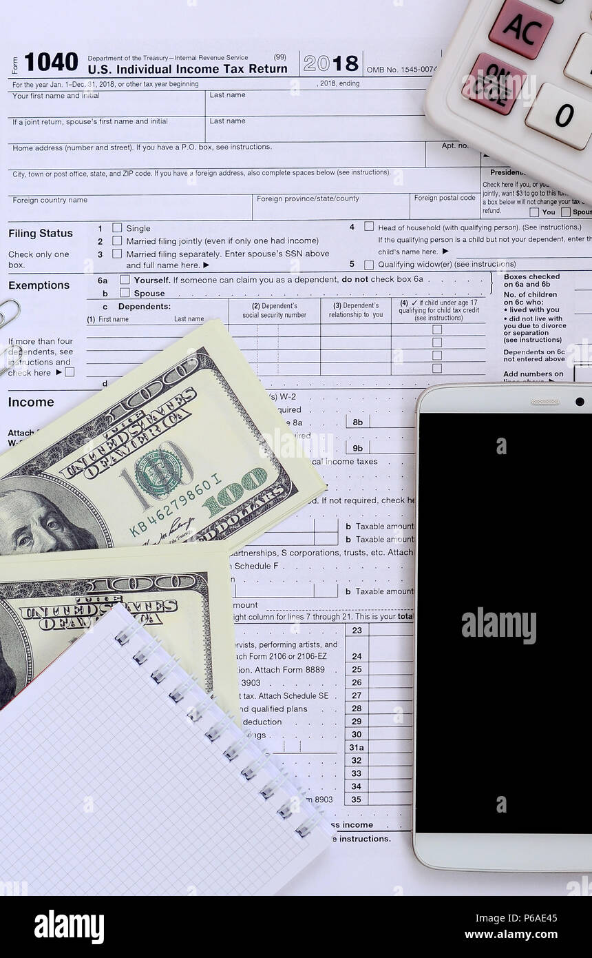 Zusammensetzung der Elemente liegen auf dem 1040 Steuerformular. Dollarscheine, Rechner, Smartphone, Büroklammer und Notepad. Die Zeit, die Steuern zu bezahlen. Stockfoto