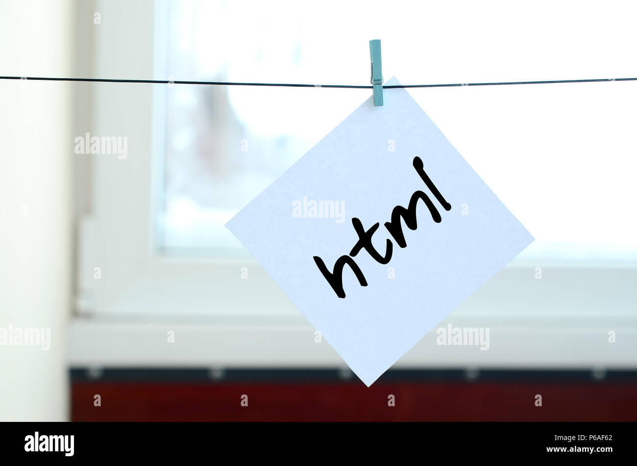 Html. Hinweis befindet sich auf einem weißen Aufkleber, die mit einer Wäscheklammer an einem Seil auf einem Hintergrund von Fensterglas hängt geschrieben. Stockfoto