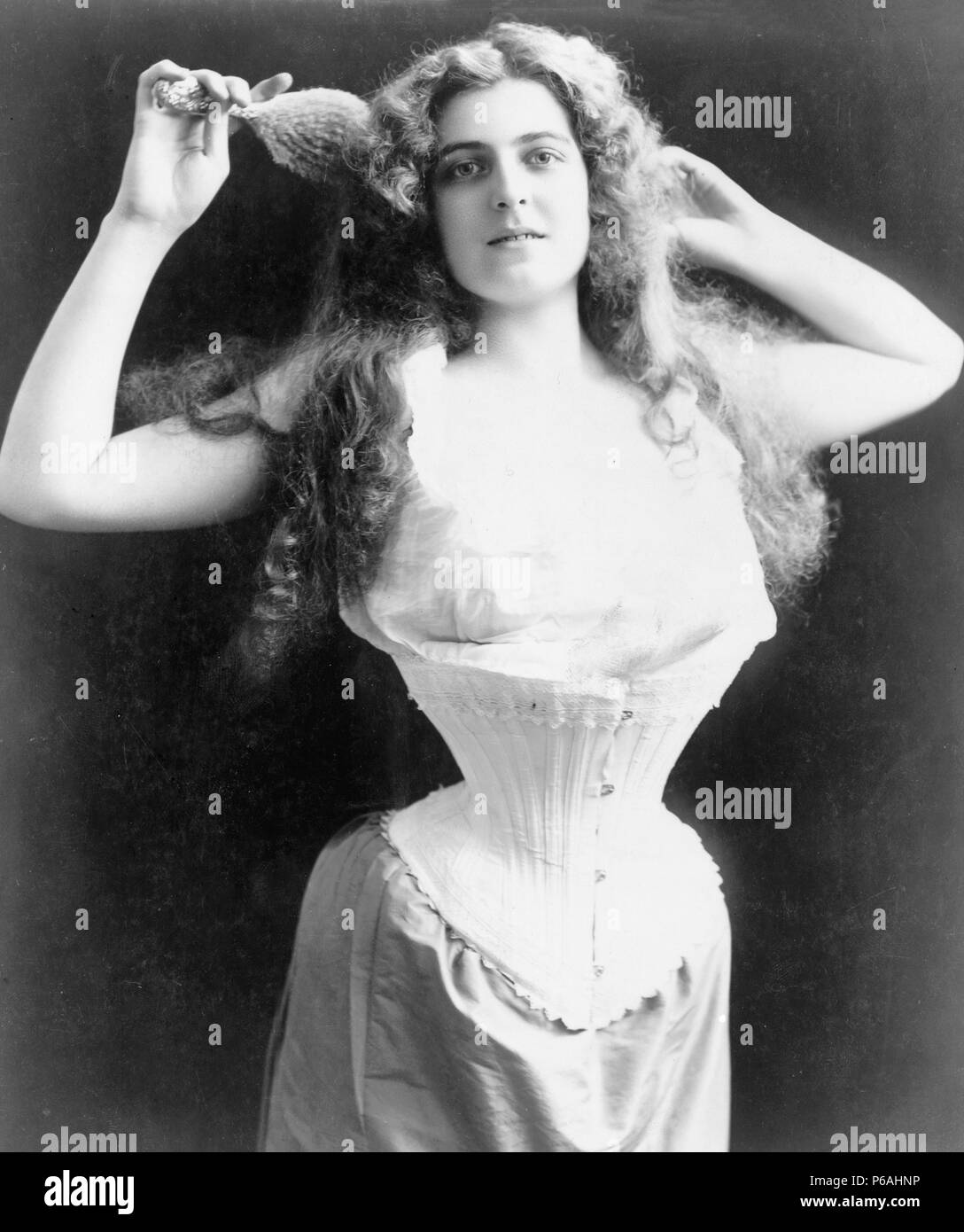 Frau tragen Korsett, Bürsten ihr Haar, Brustbild, stehend, nach vorne, ca. 1899 Stockfoto
