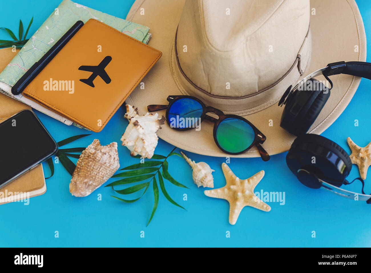 Elegante schwarze Telefon, Reisepass, Sonnenbrille, Karte, Hut, Kopfhörer, Muscheln, Notebook am trendigen blau Papier. Flach. Planung sommer urlaub Konzept. tr Stockfoto