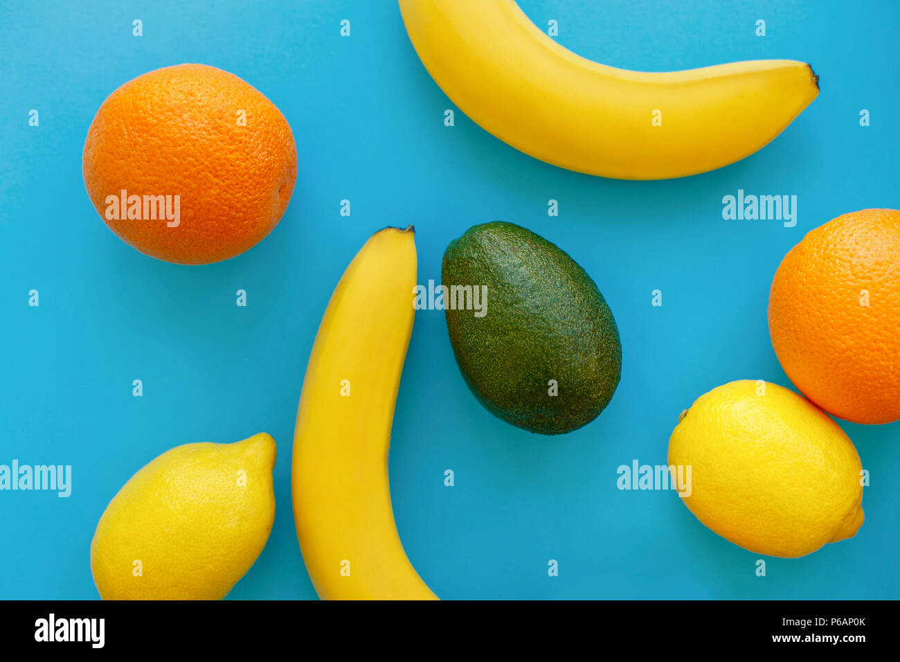 Bananen, Orangen-, Avocado- und Zitronen auf hellen blauen Papier, trendige Flach. Moderne Sommer Bild Konzept. multi Frucht Flach, saftige Vitamin Abstract Stockfoto
