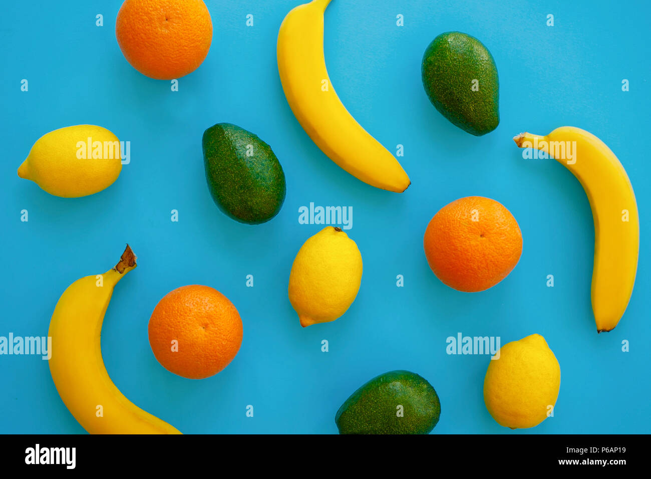 Früchte trendige Flach. Bananen, Orangen-, Avocado- und Zitronen auf hellen blauen Papier. Moderne Sommer Bild Konzept. multi Frucht Flach, saftige Vitamin ab Stockfoto