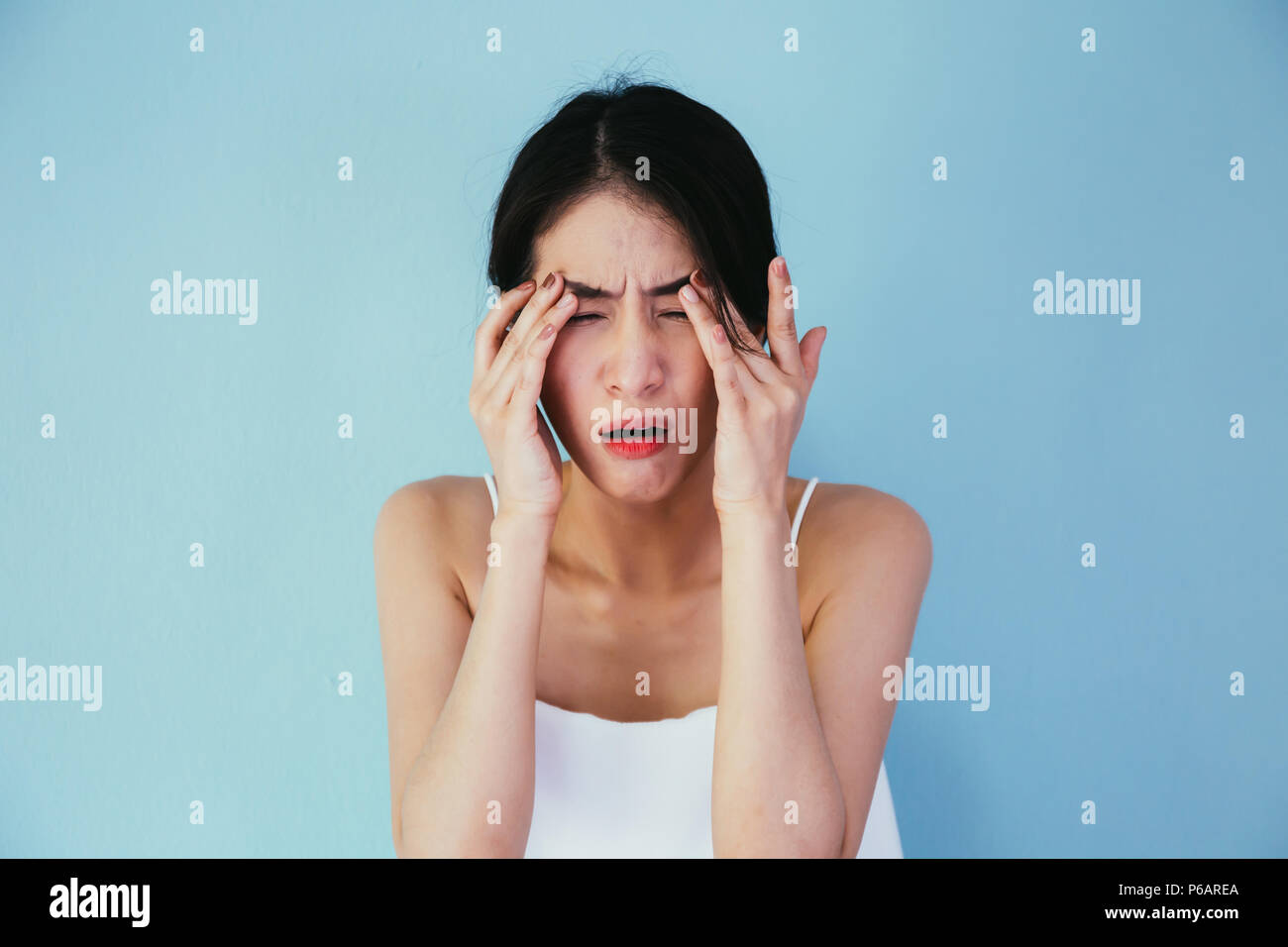 Junge asiatische Frau, die Augen schmerzen und Druckempfindlichkeit isoliert über blauer Hintergrund - Gesundheitswesen und medizinische Konzept Stockfoto