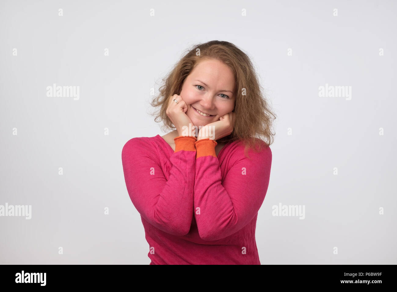 Lächelnd europäische Dame in rosa Pullover an Kamera suchen und lächelnd auf grauem Hintergrund. Selbstbewusst und unabhängig sein. Art ezpression o Stockfoto