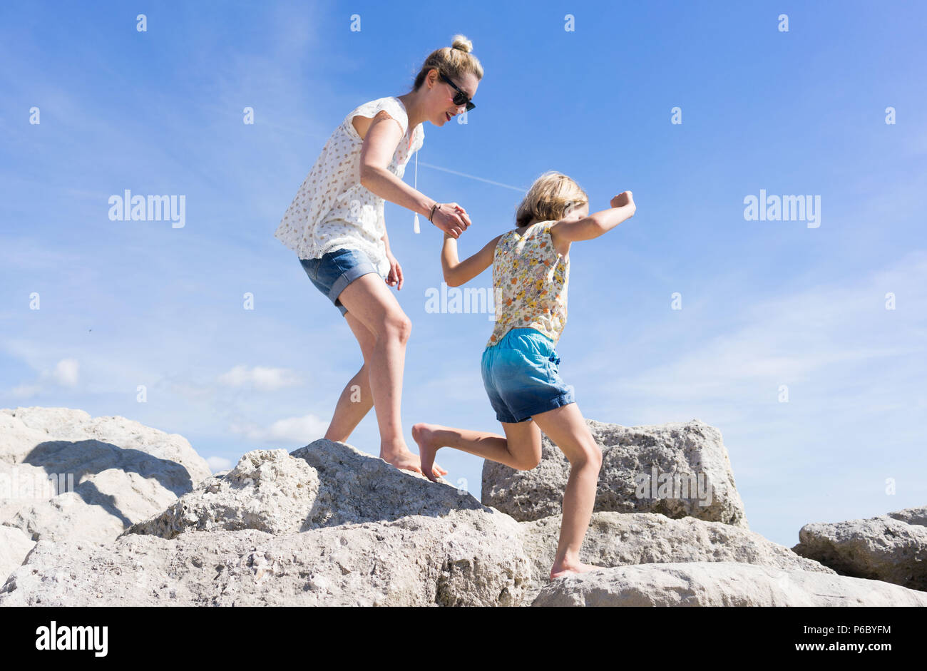 Mutter und Tochter spazieren und Klettern auf den Felsen am Meer Stockfoto