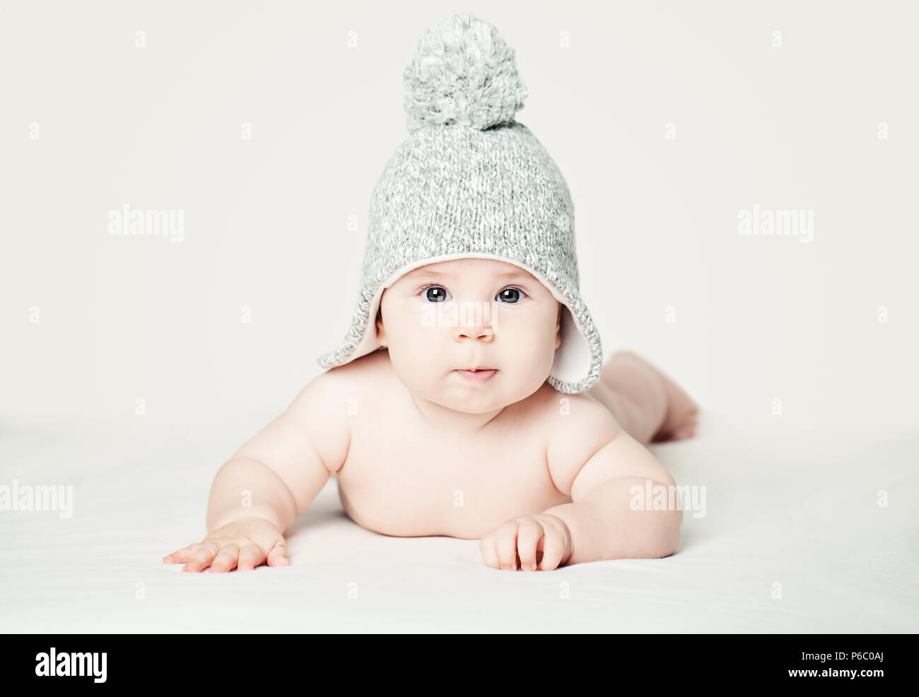 Baby in Strickmütze liegen auf weißen blankett, Portrait. Hübsches kleines Kind (3 Monate alt) Stockfoto