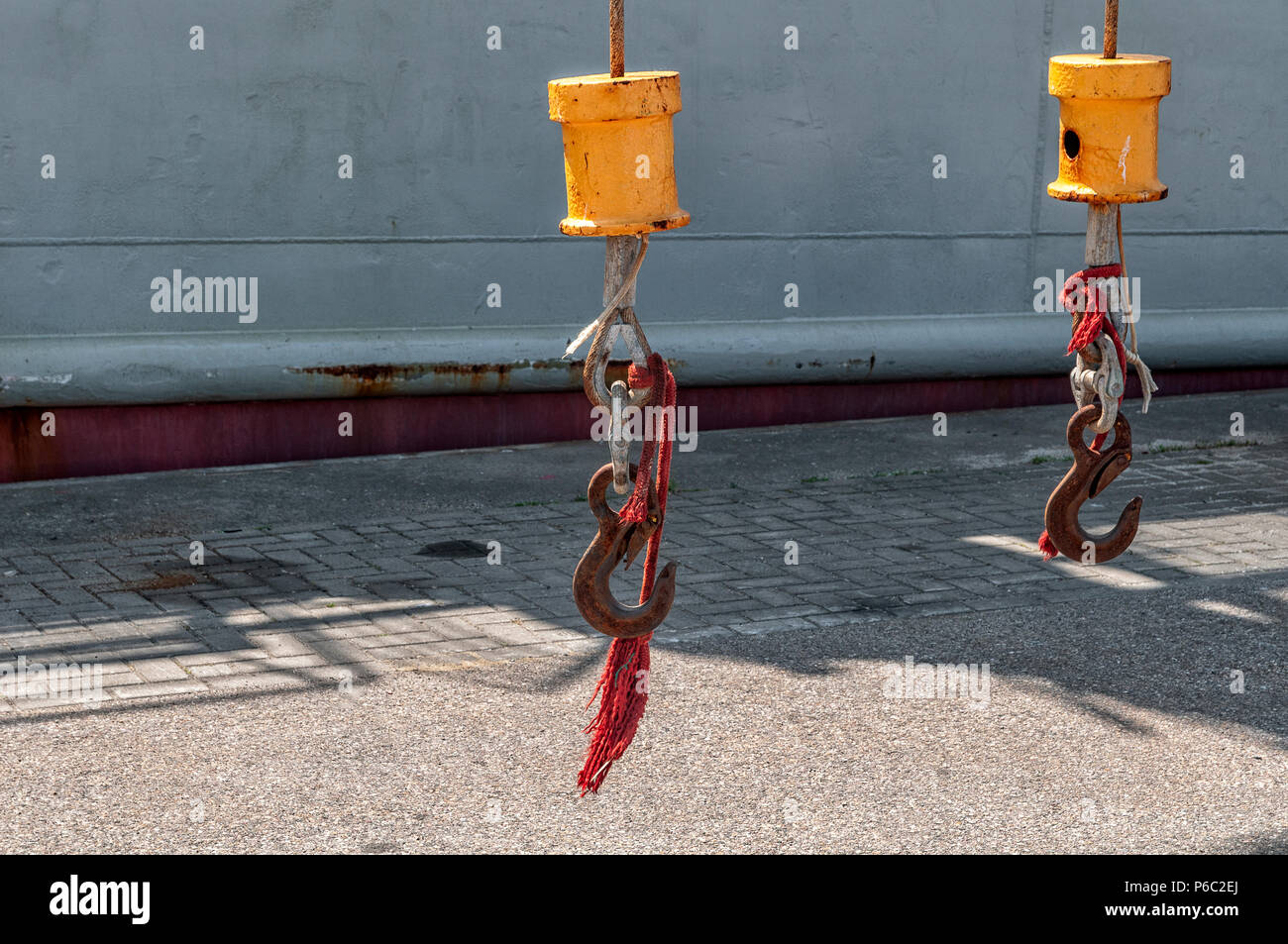 Zwei Kranhaken hängen in der Nähe von einem Seeschiff Stockfoto