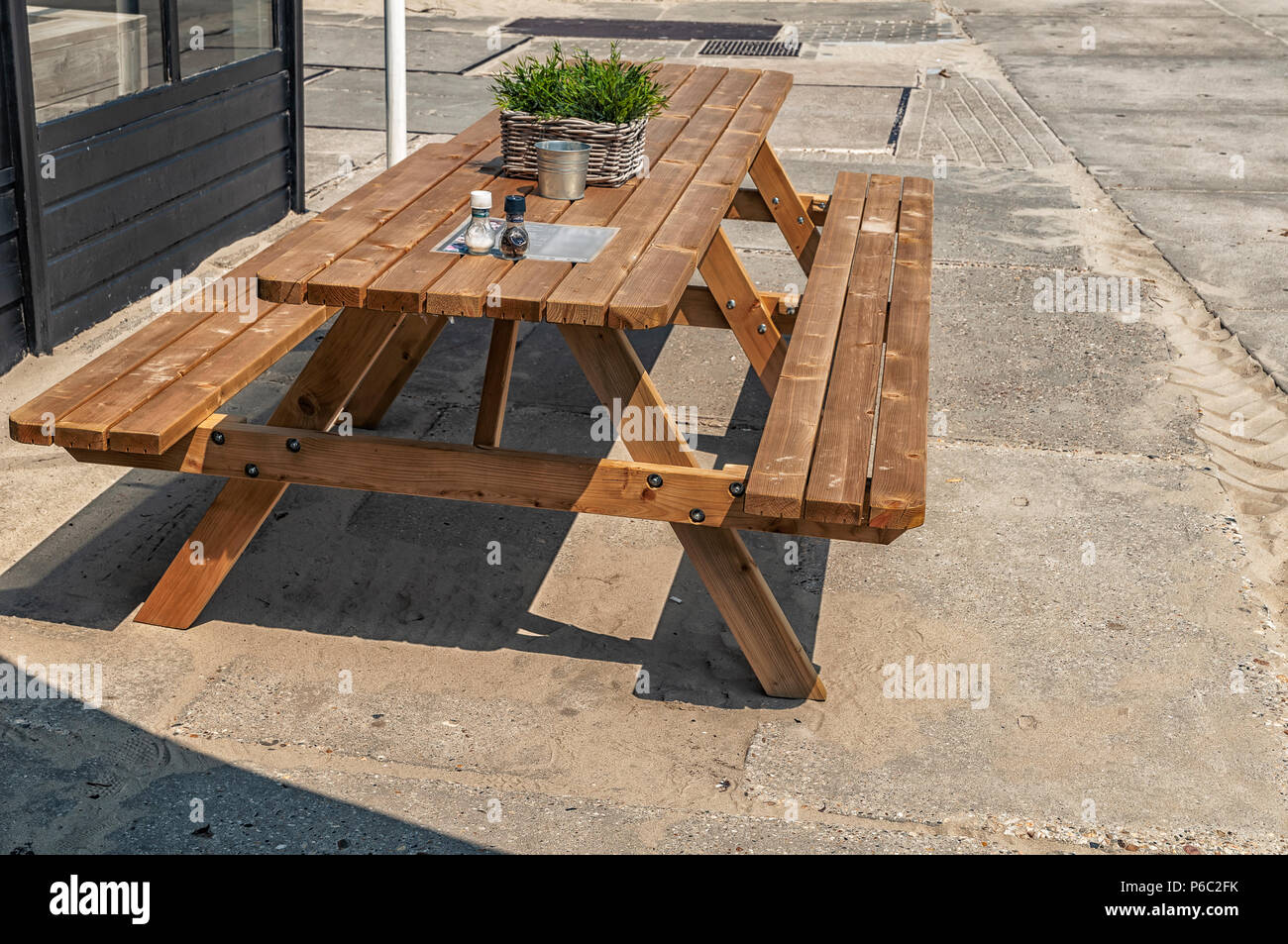 Bank aus Holz auf einem Betonboden in der Nähe des Strandes Stockfoto