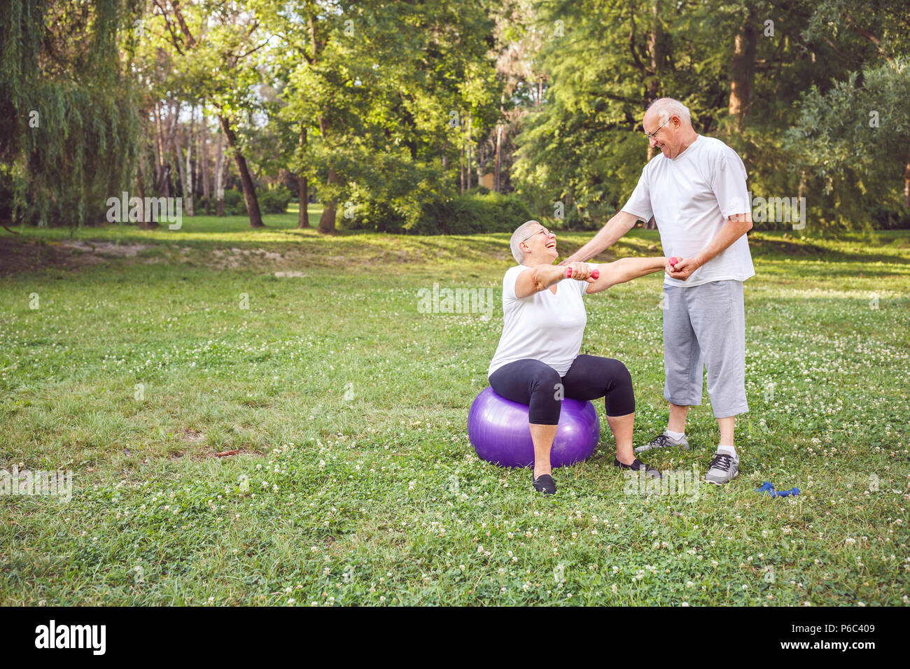 Konzept der gesunden Lebensstil - Lächelnd reifer Mann und Frau zusammen tun Fitness Übungen auf Fitness Ball im Park Stockfoto