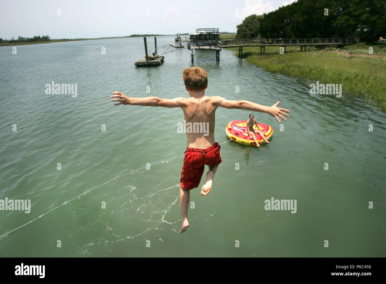 Ein Junge springt von einem Dock in einen Fluss außerhalb von Savannah, Georgia. Stockfoto