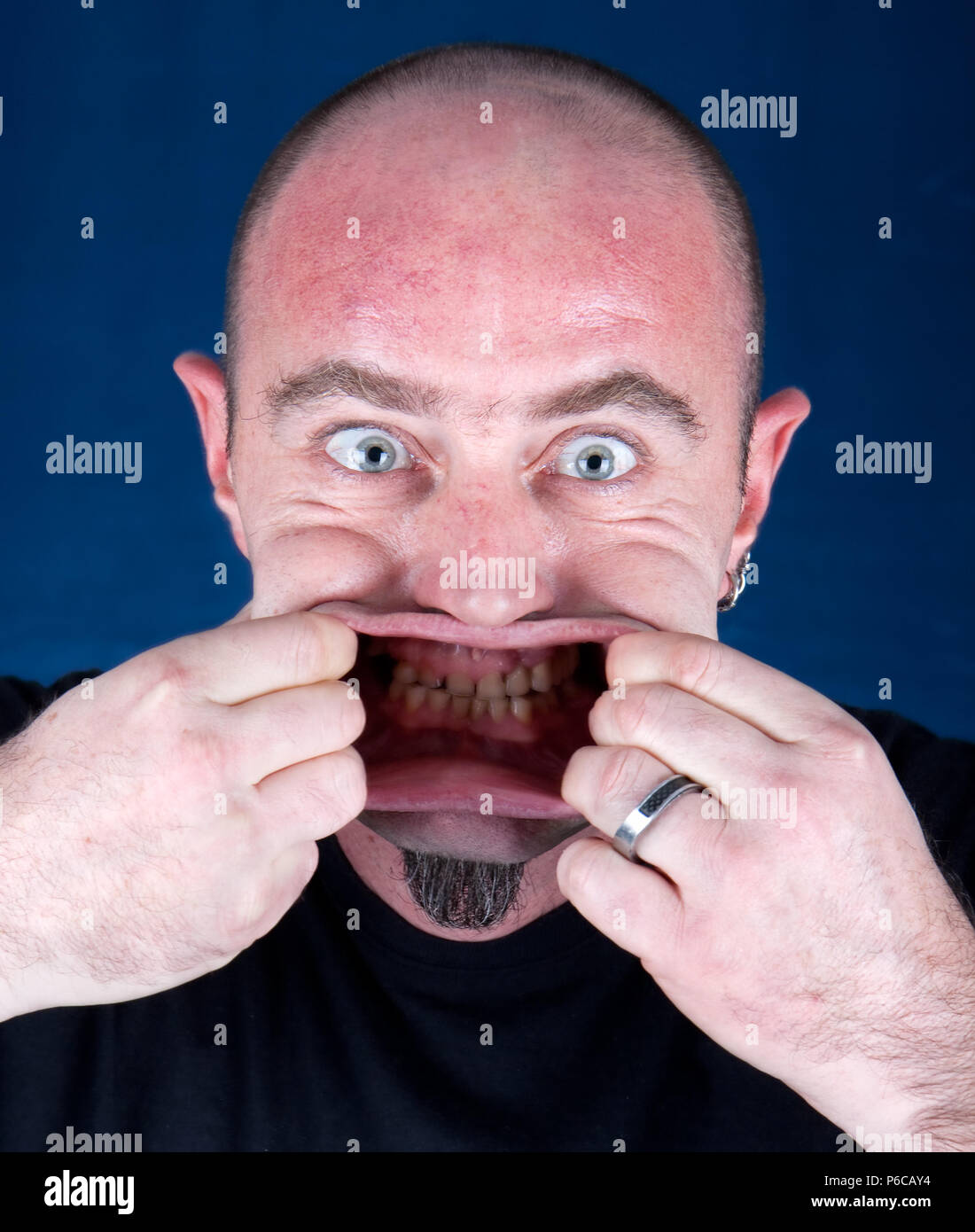 Mann seinen Mund stretching ein lustiges Gesicht machen, Studio shot Stockfoto