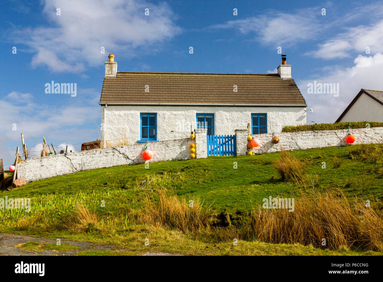 Ein weiß getünchtes Ferienhaus in Fionnphort auf dem Ross von Mull ist mit der farbefrohen Fisherman marker Bojen, Argyll und Bute, Schottland, Großbritannien eingerichtet Stockfoto