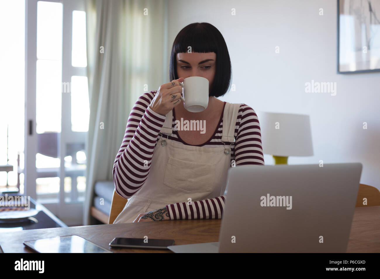Frau mit Kaffee, während mit Laptop zu Hause Stockfoto