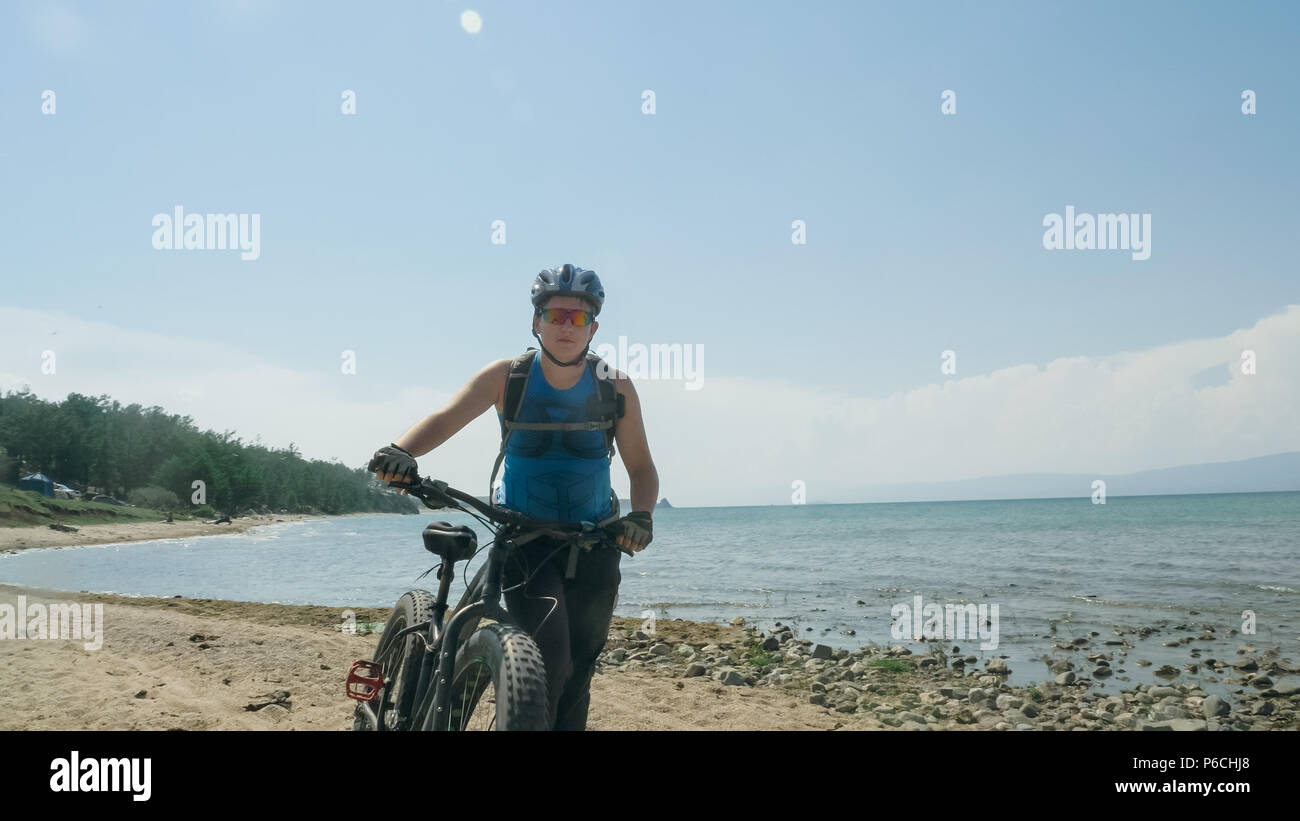 Fat bike auch fatbike oder Fat Tire Bike im Sommer fahren am Strand. Der Kerl wird direkt am Strand. Auf dem Sand auf einer solchen Fahrt mit dem Fahrrad Stockfoto