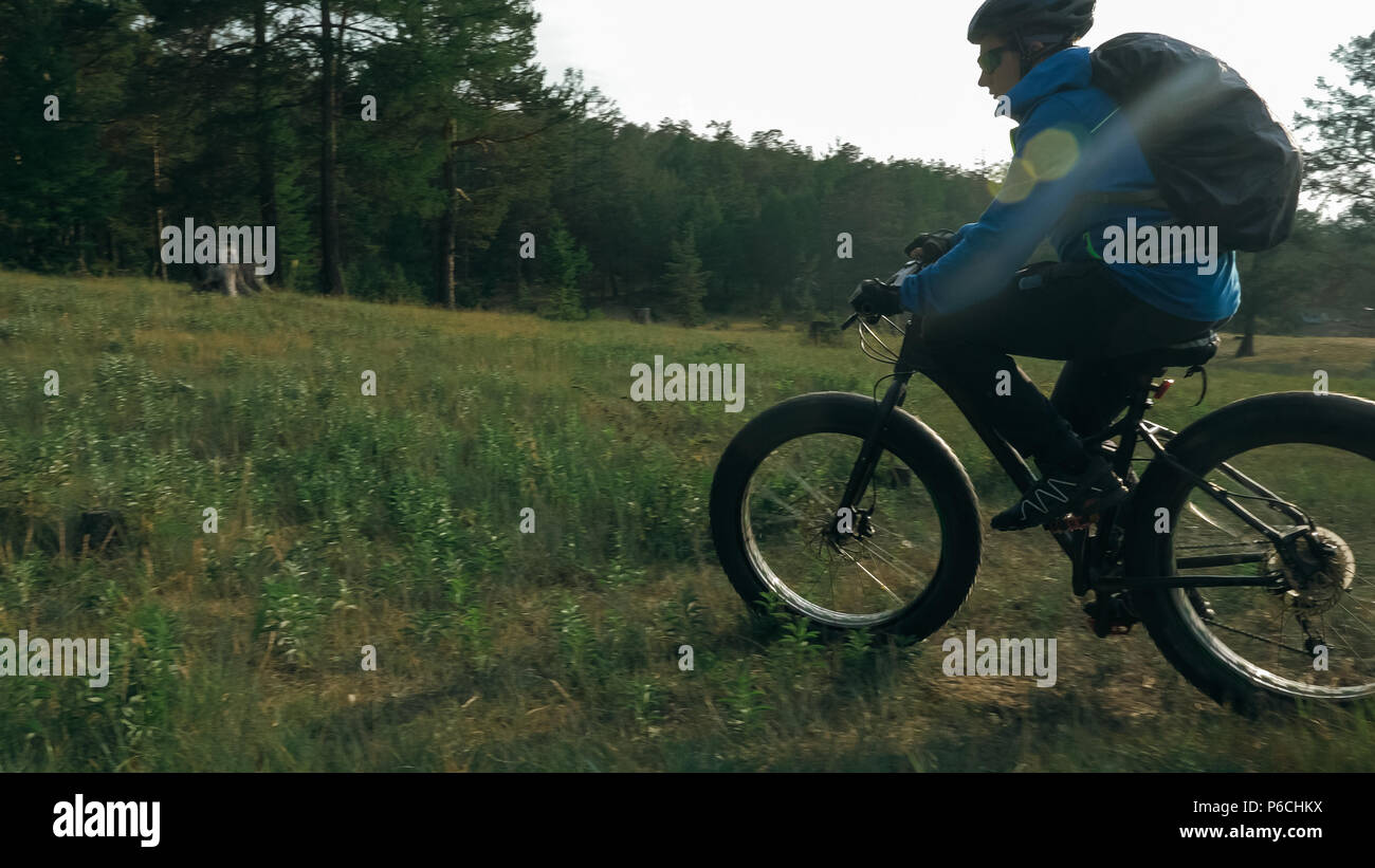 Fat bike auch fatbike oder Fat Tire Bike im Sommer Reiten im Wald. Der Kerl fährt Fahrrad zwischen Bäumen und Stümpfe. Er überwindet einige obstac Stockfoto