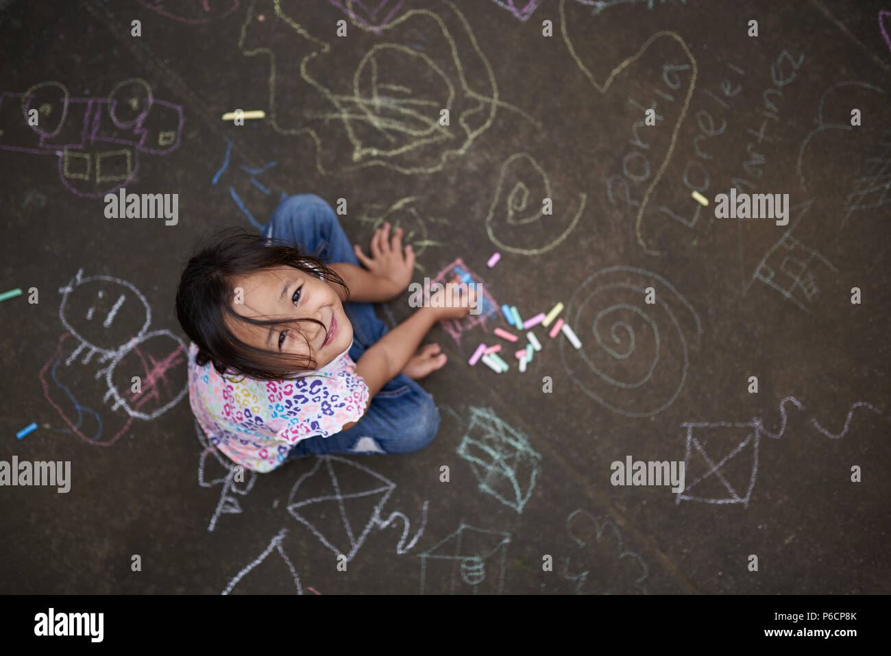 Asiatische kleines Mädchen mit Kreide auf Asphalt gemalte Hintergrund oben Ansicht von oben Stockfoto