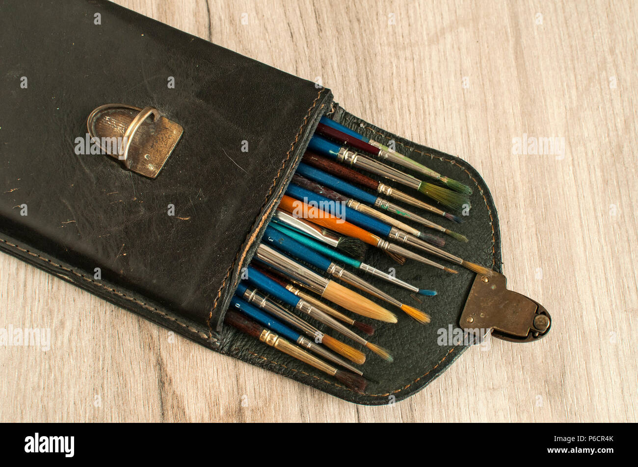 Vintage Ledertasche Kiste voll von verschiedenen Arten von verwendeten Pinsel auf Holz- oberfläche Hintergrund öffnen Stockfoto