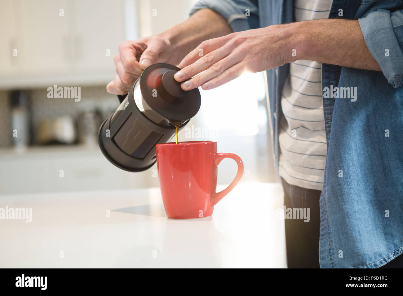 Man gießt Kaffee aus der französischen Presse in Becher zu Hause Stockfoto