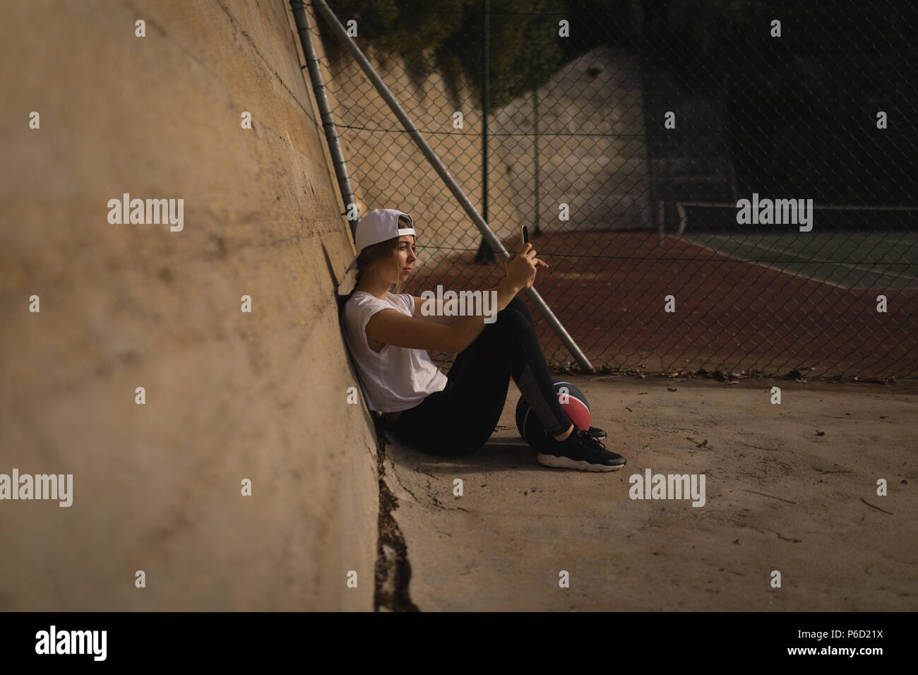 Frau mit Handy in den Basketballplatz Stockfoto
