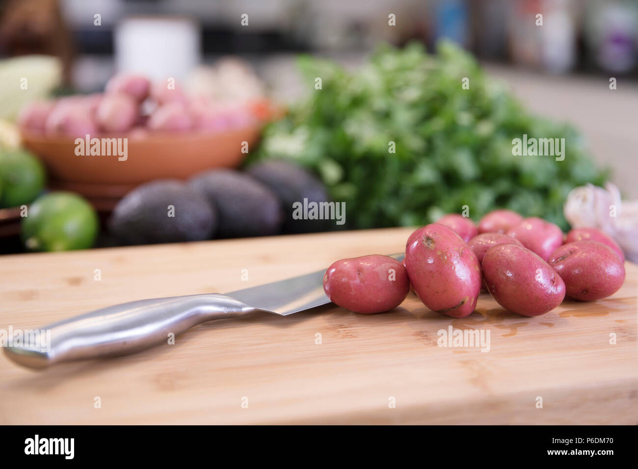 Kleine rote Kartoffeln auf Schneidebrett mit Messer in der Küche Stockfoto